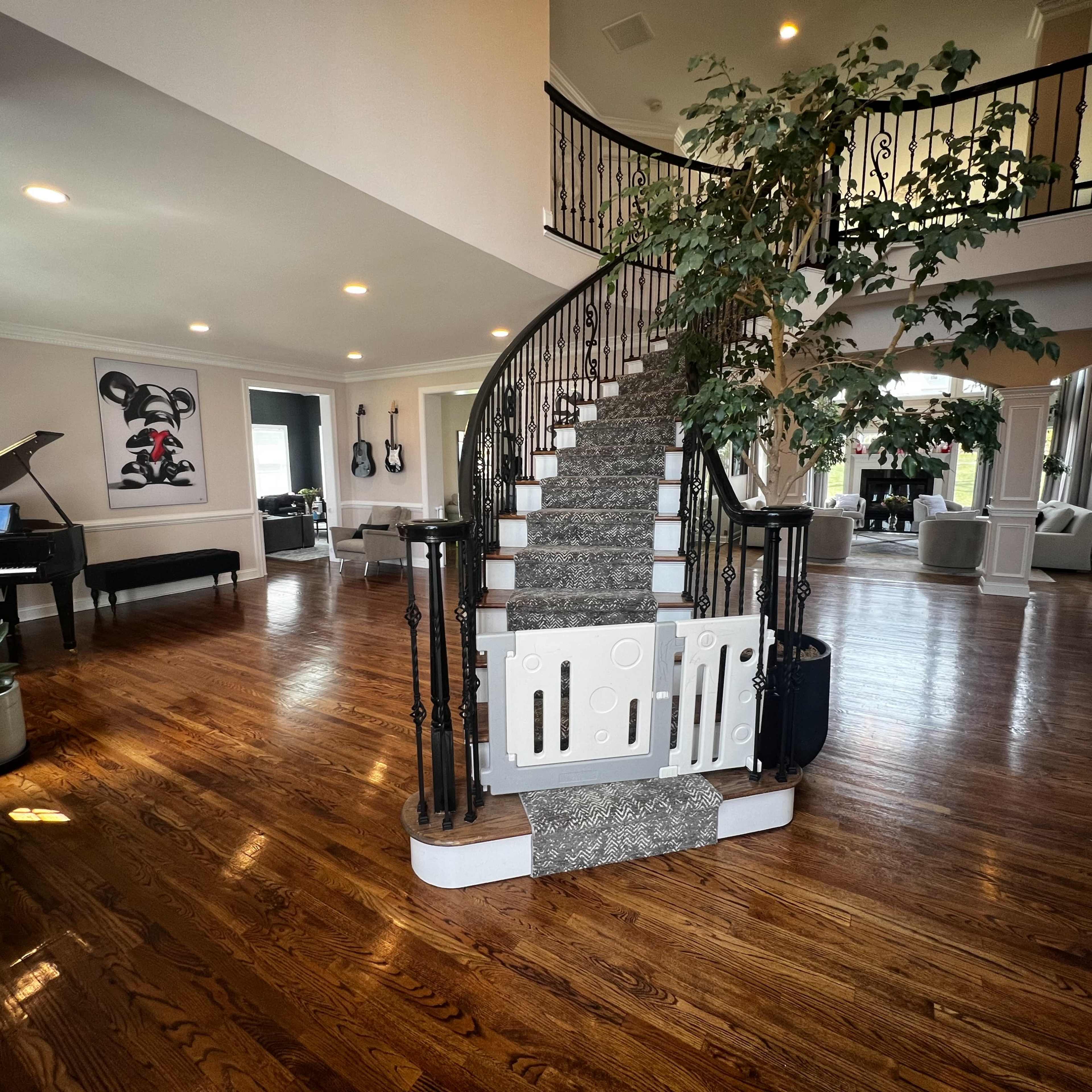 A spacious foyer with a staircase leading to an upper level, a grand piano in the corner, and a large plant near the entrance.