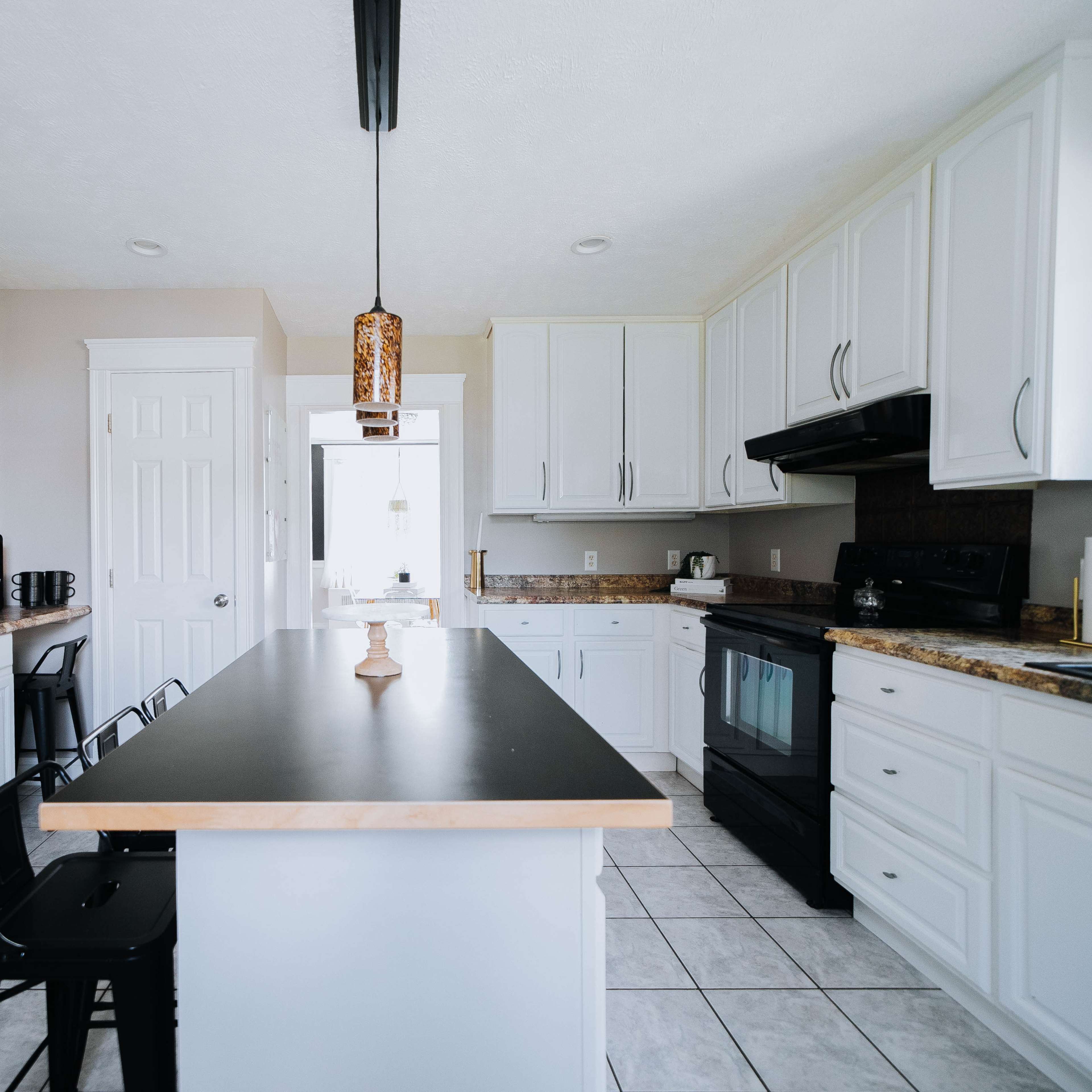 A modern kitchen with white cabinetry, a central island, and a countertop with appliances and seating.