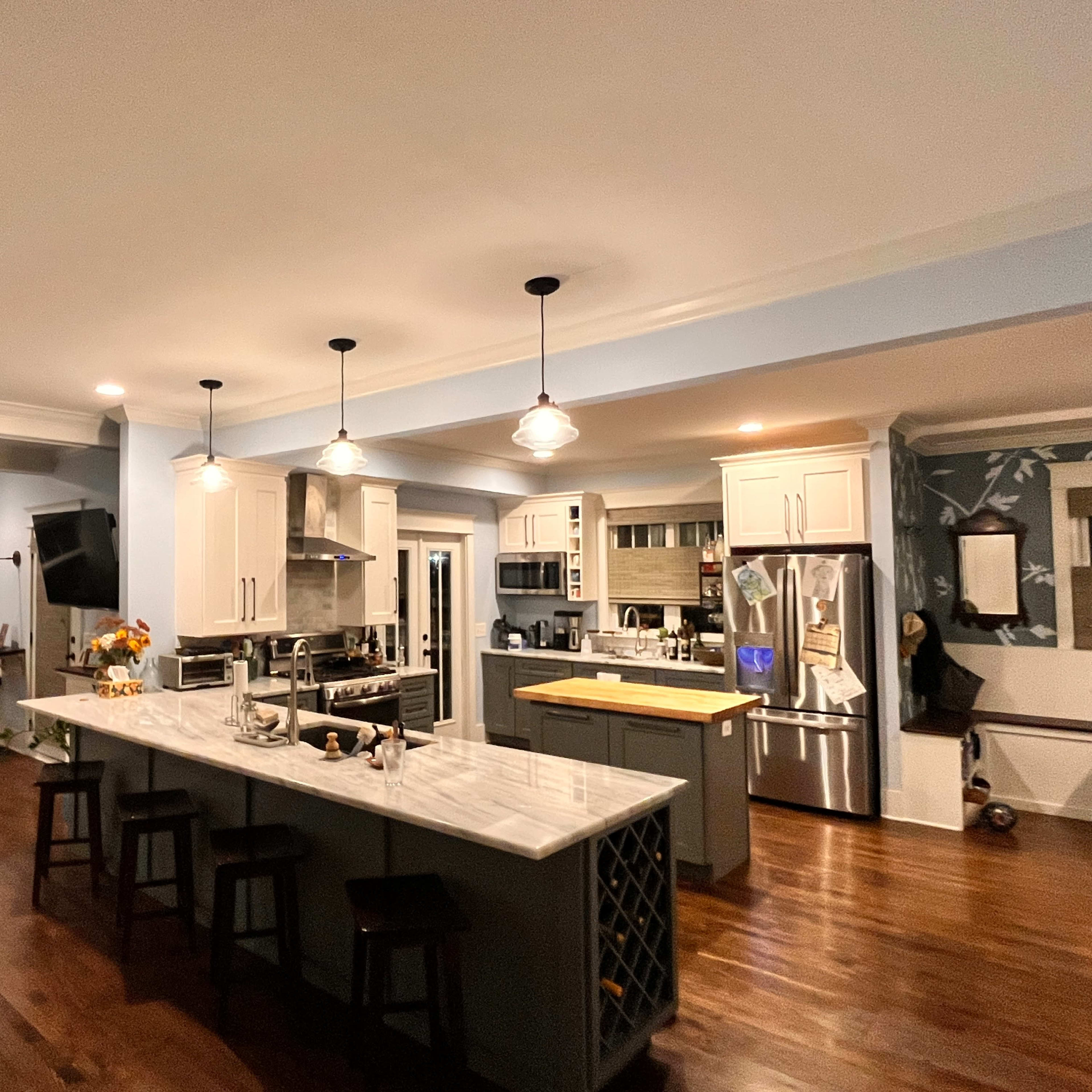 A modern kitchen with a large island, stainless steel appliances, and wooden flooring.