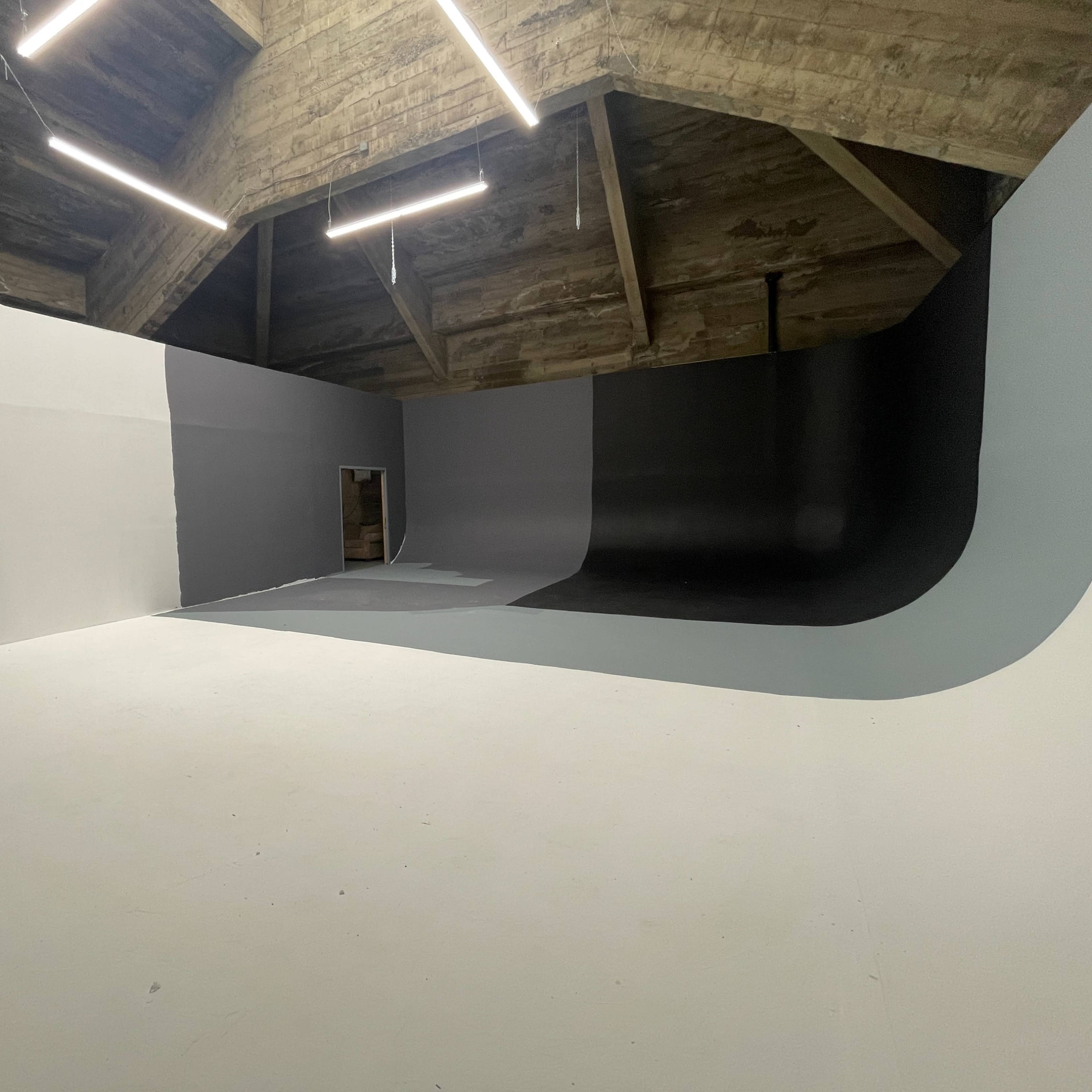 A spacious room with a curved wall design that features three different shades of gray and a door at one end.