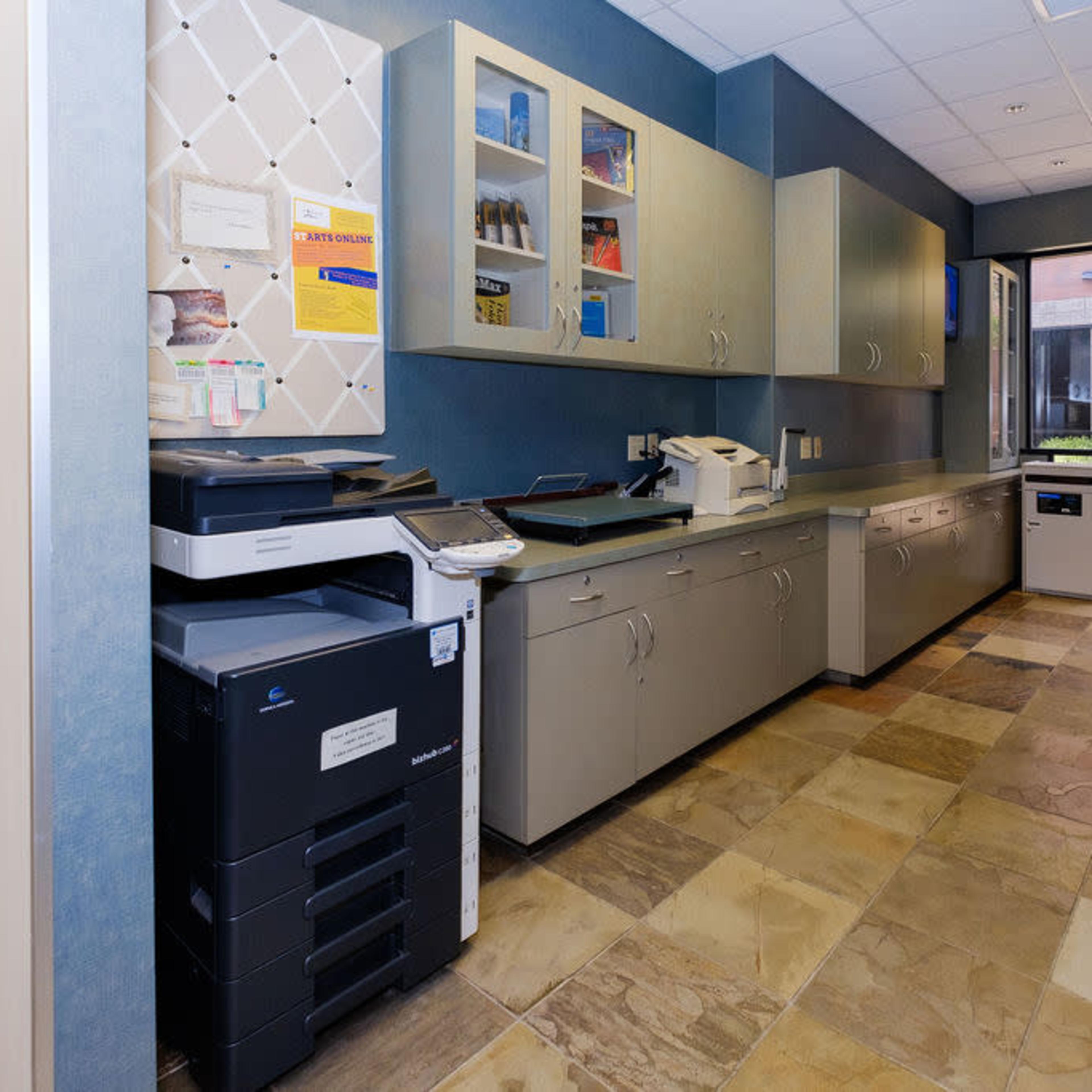 A corridor featuring a photocopy machine, cabinets, and a door leading to an outdoor area.