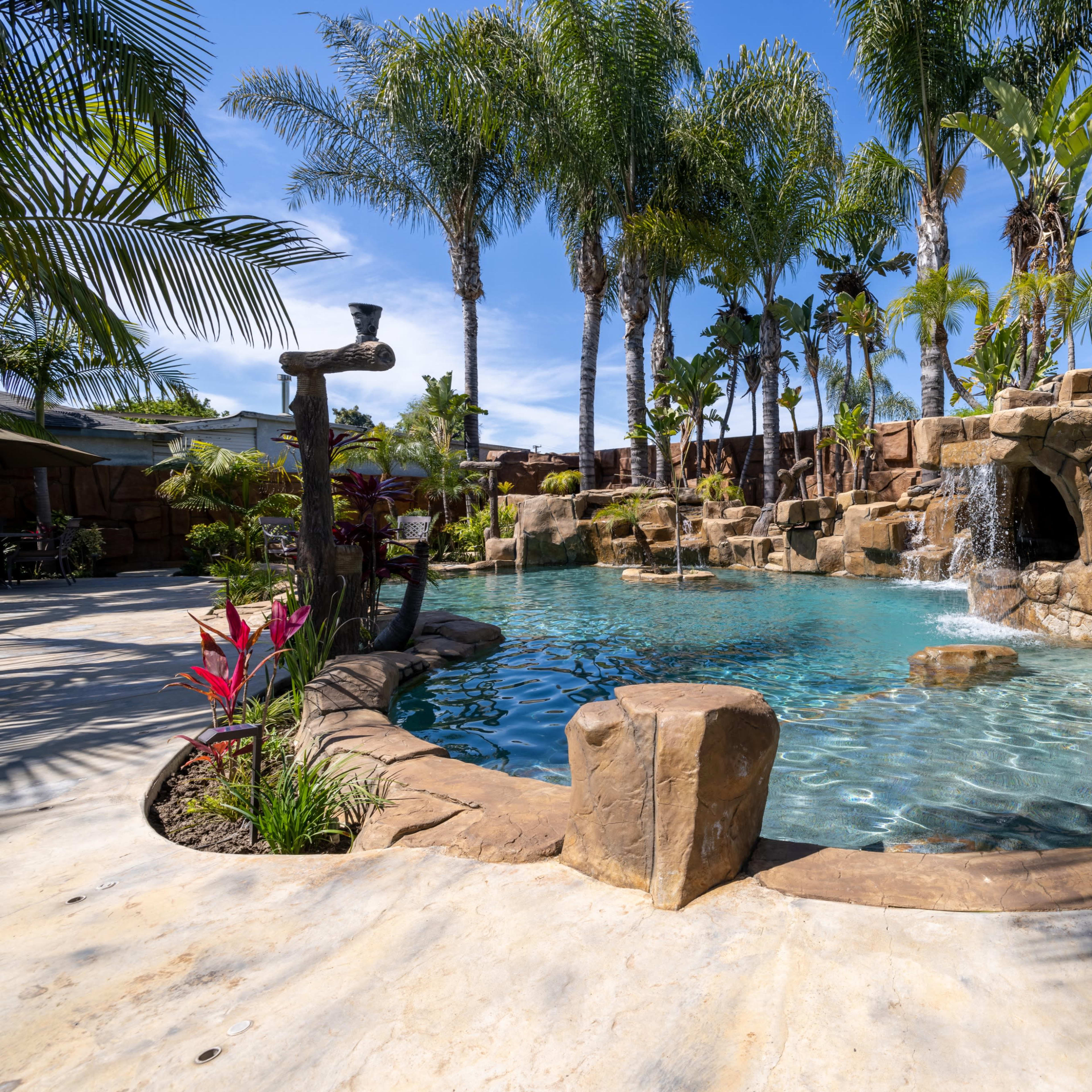 A landscaped pool area surrounded by tropical plants and rock formations.