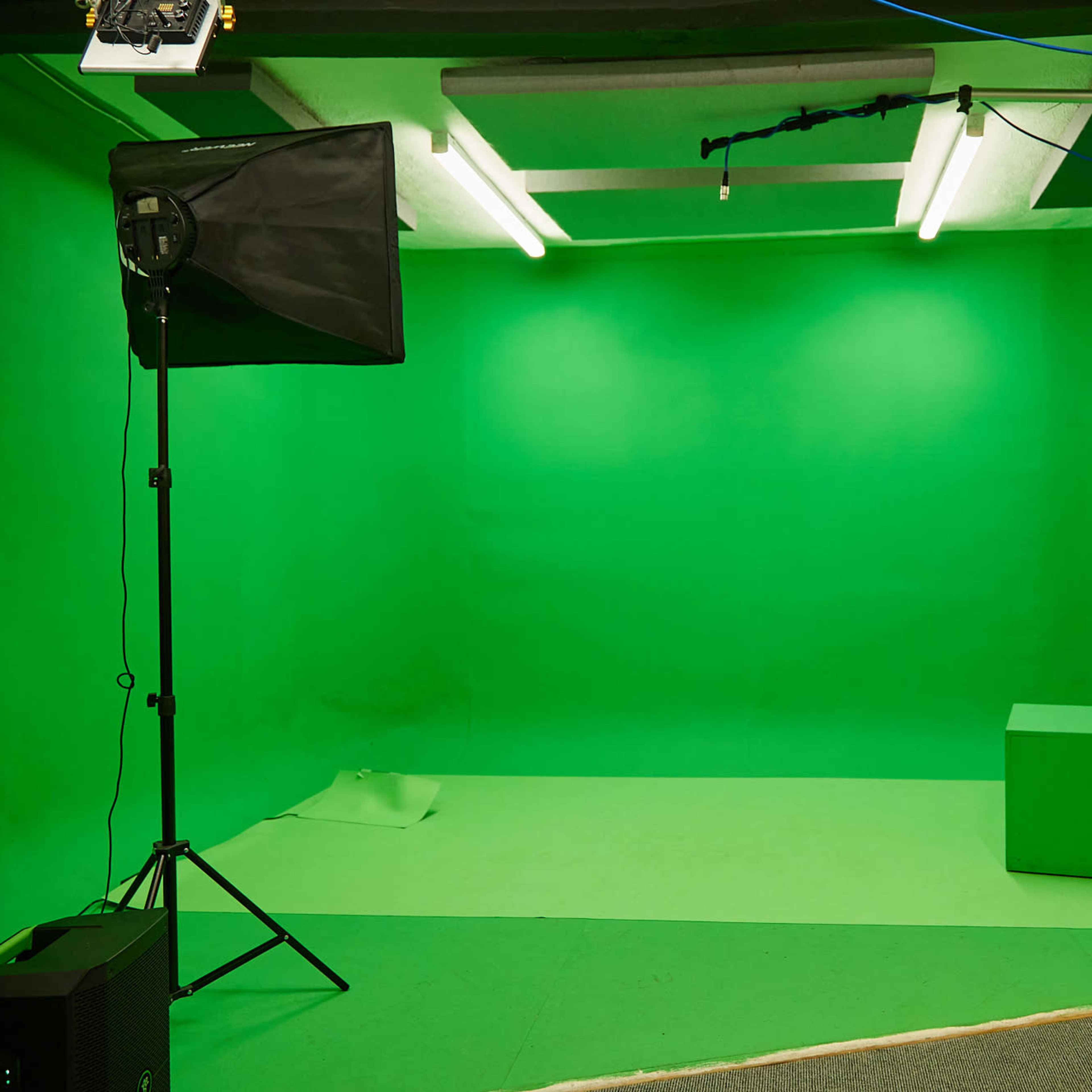 A green screen room with a spotlight, backdrop, and a green cube in the center.