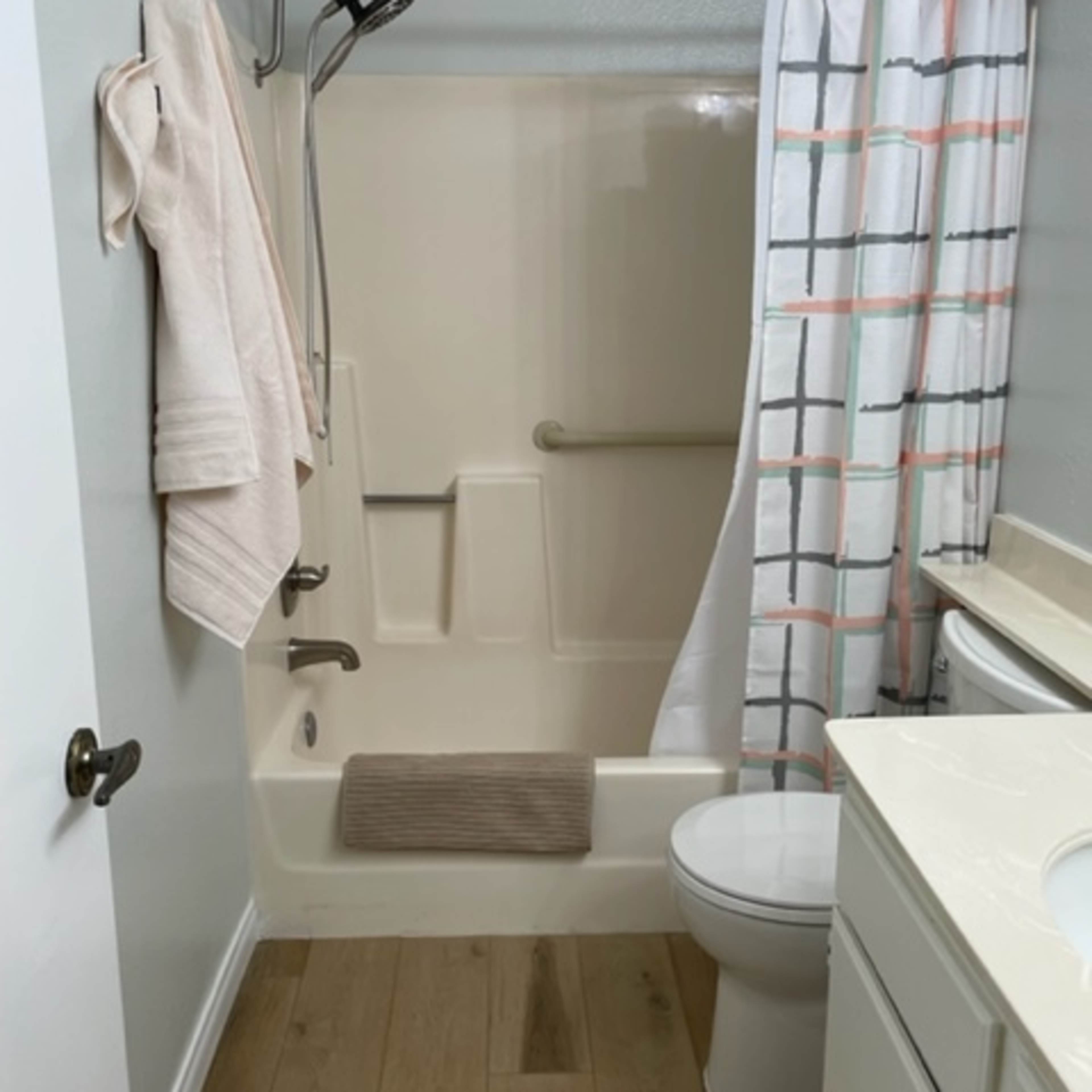 A bathroom featuring a shower with a curtain, a toilet, a sink with a countertop, and beige wall and flooring.