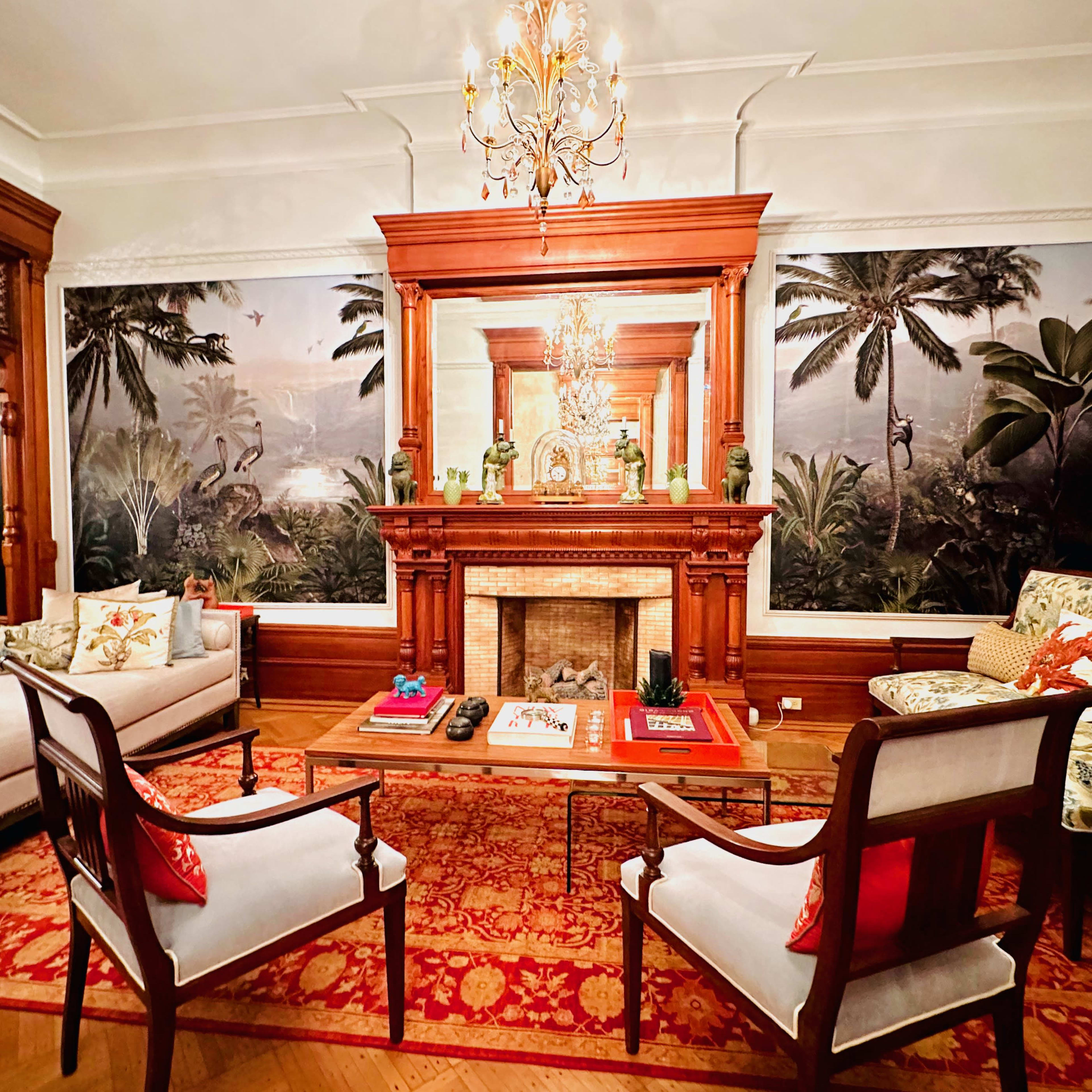 The living room features a wooden-framed fireplace surrounded by upholstered seating and tropical-themed wall murals.