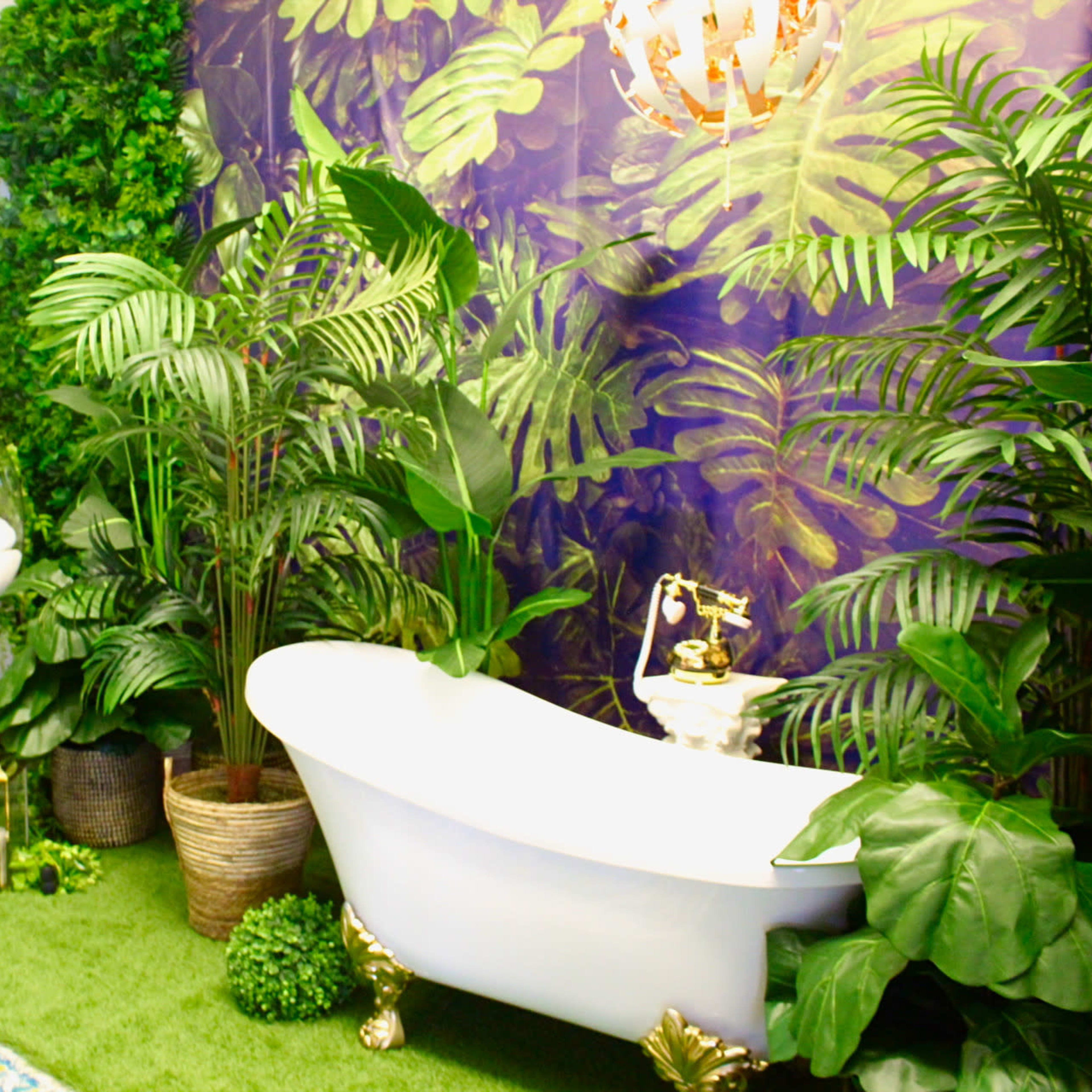 A bathroom decor with a vintage bathtub surrounded by lush greenery, a hanging chair, and decorative plants against a patterned purple wall.