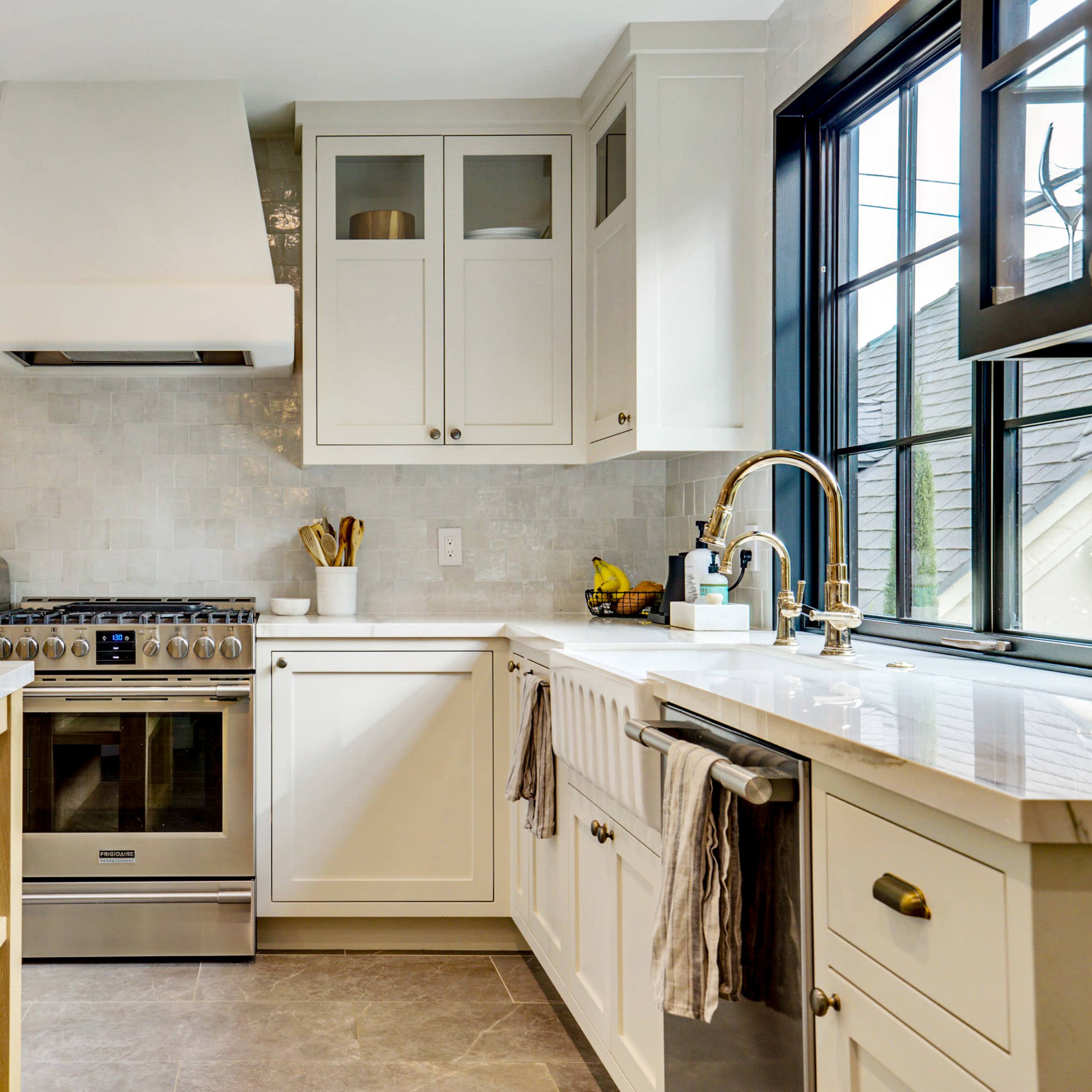 A modern kitchen with white cabinetry, a stainless steel stove, and a large island with a marble countertop.