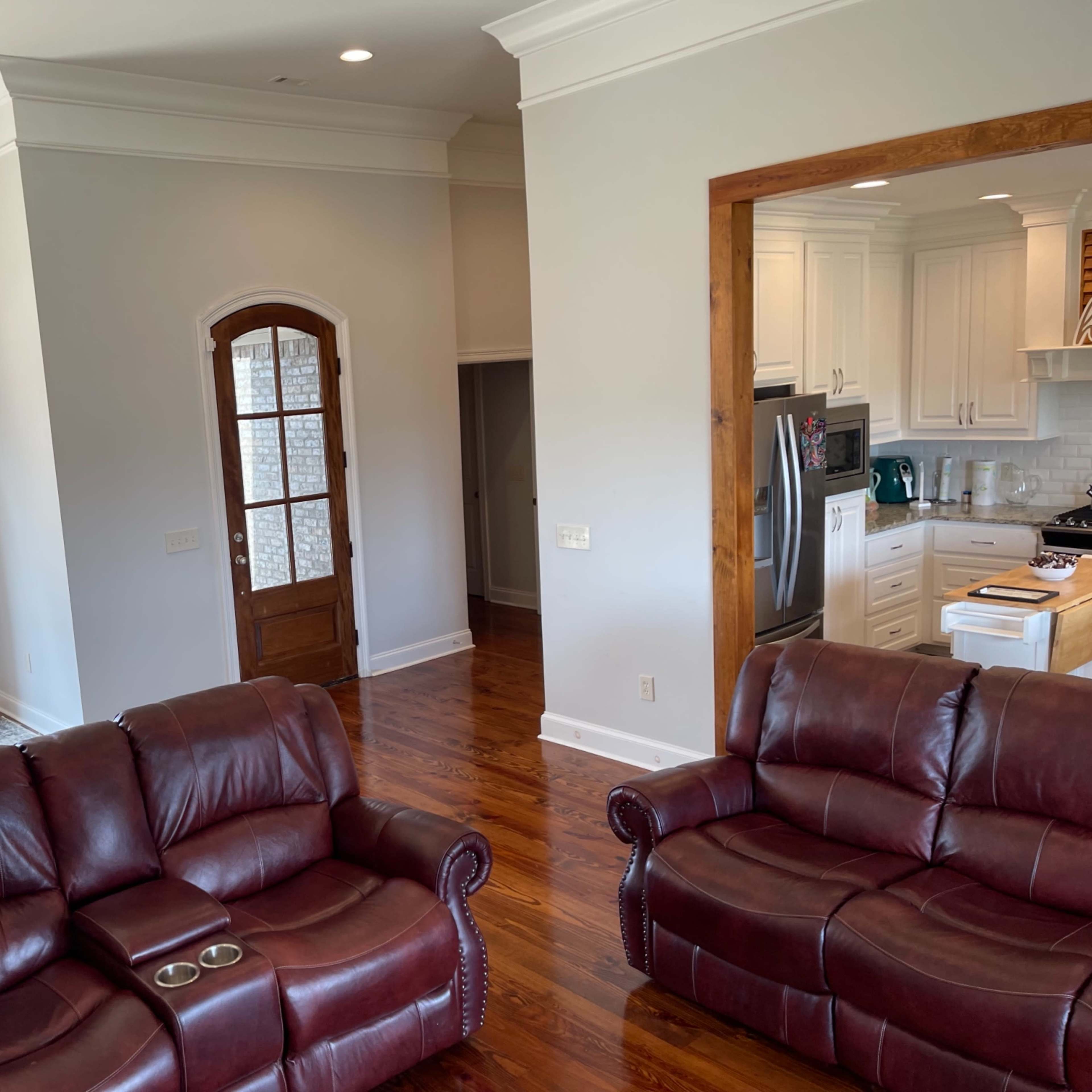 A modern living room with two brown leather sofas facing a dining area and a kitchen.