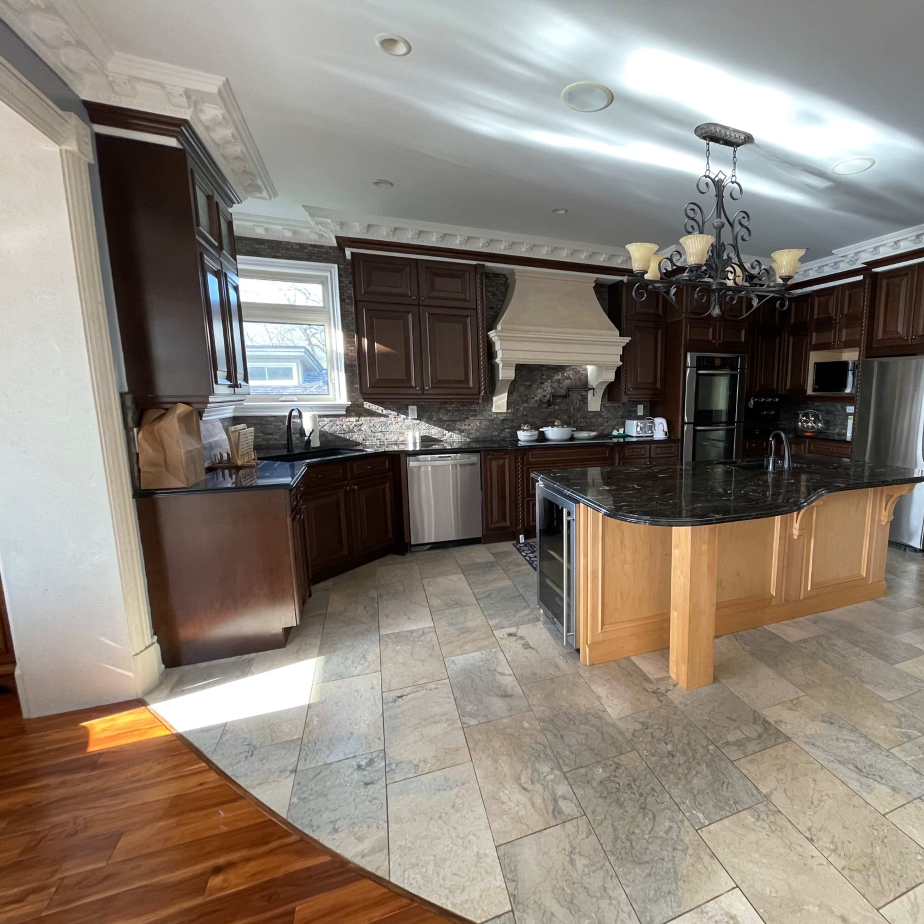 A spacious kitchen featuring dark wooden cabinets, a large granite island, and stainless steel appliances.