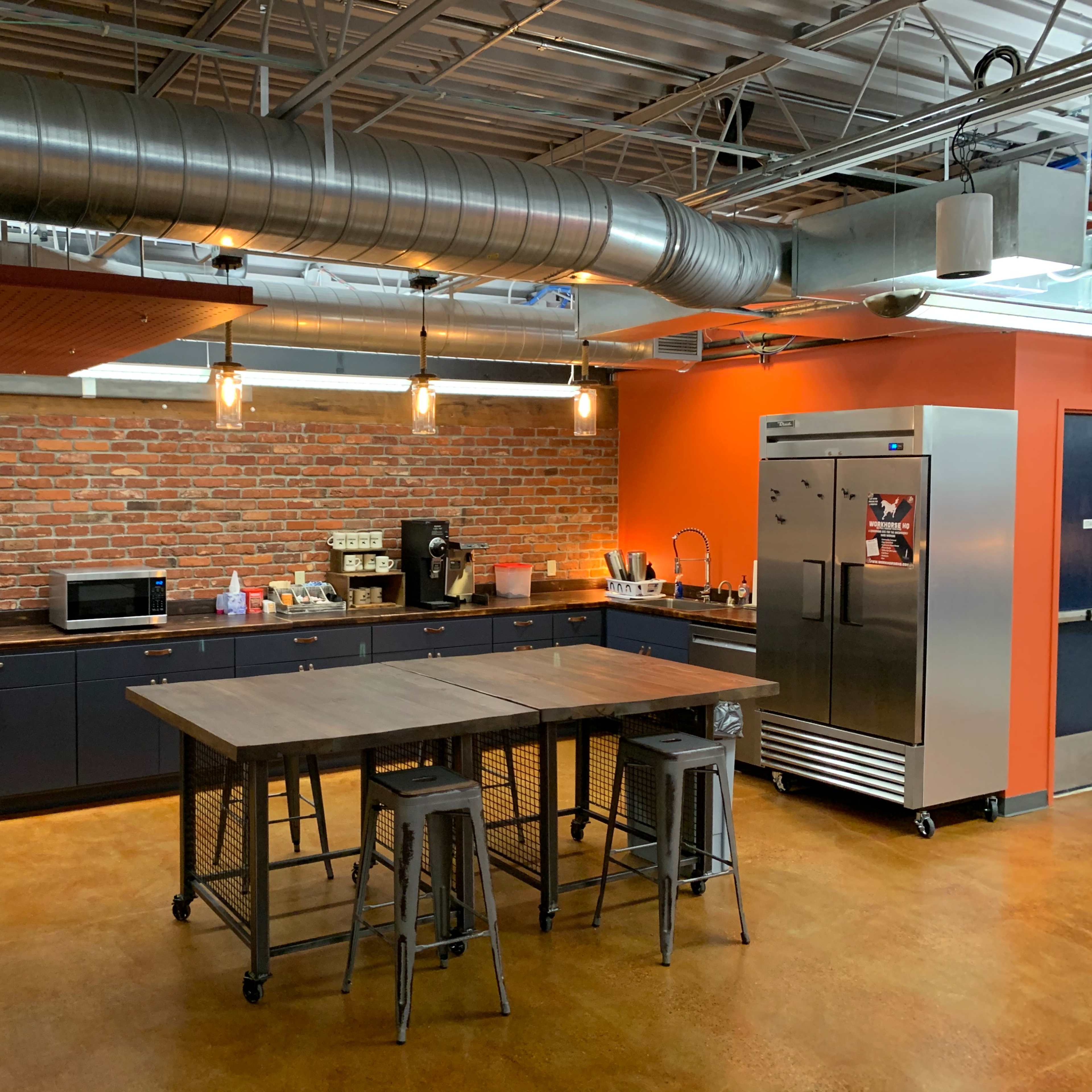 A modern kitchen with exposed brick walls, a large central island, and stainless steel appliances.