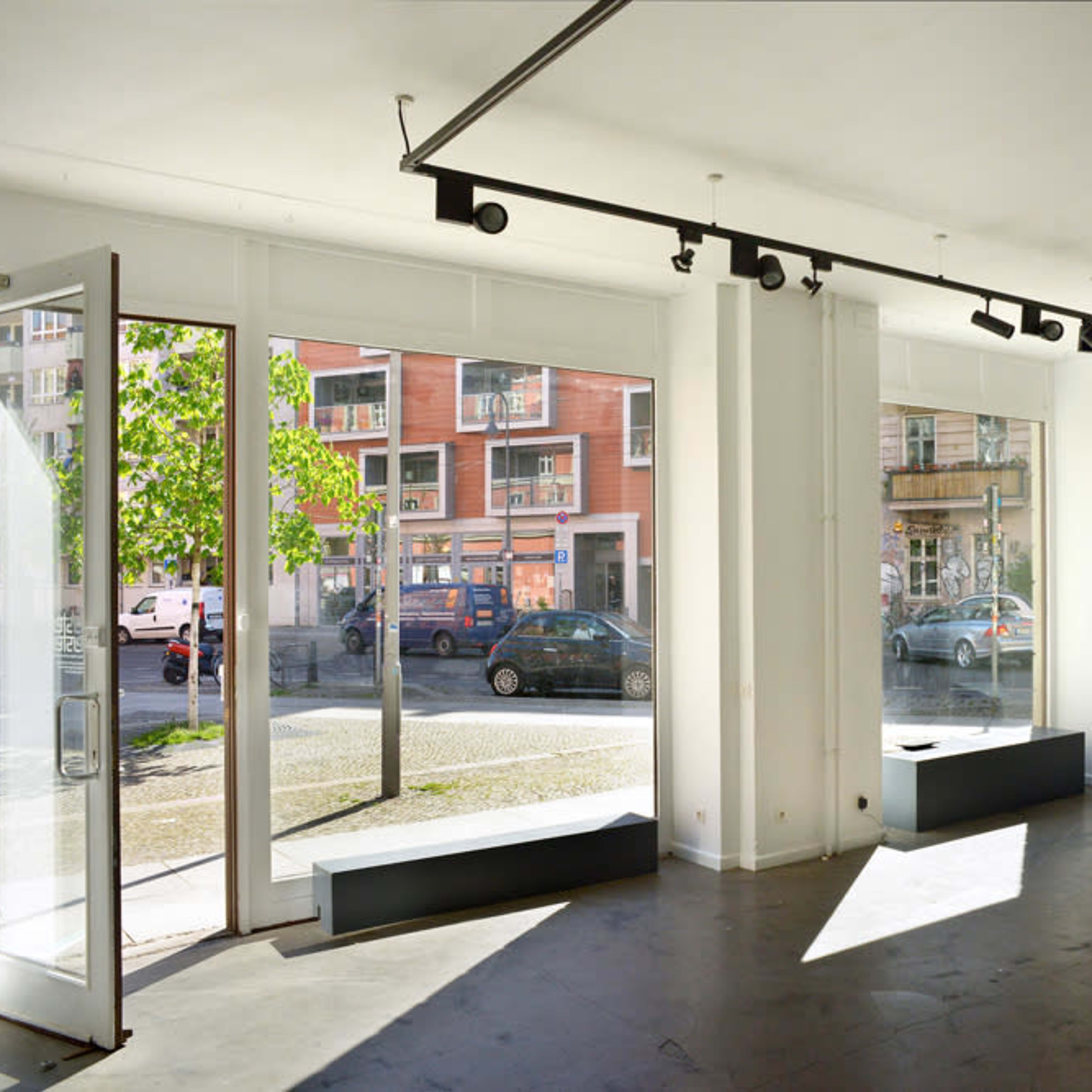 A bright, open room with large windows and a minimalist design, featuring an unobstructed view of a street outside.