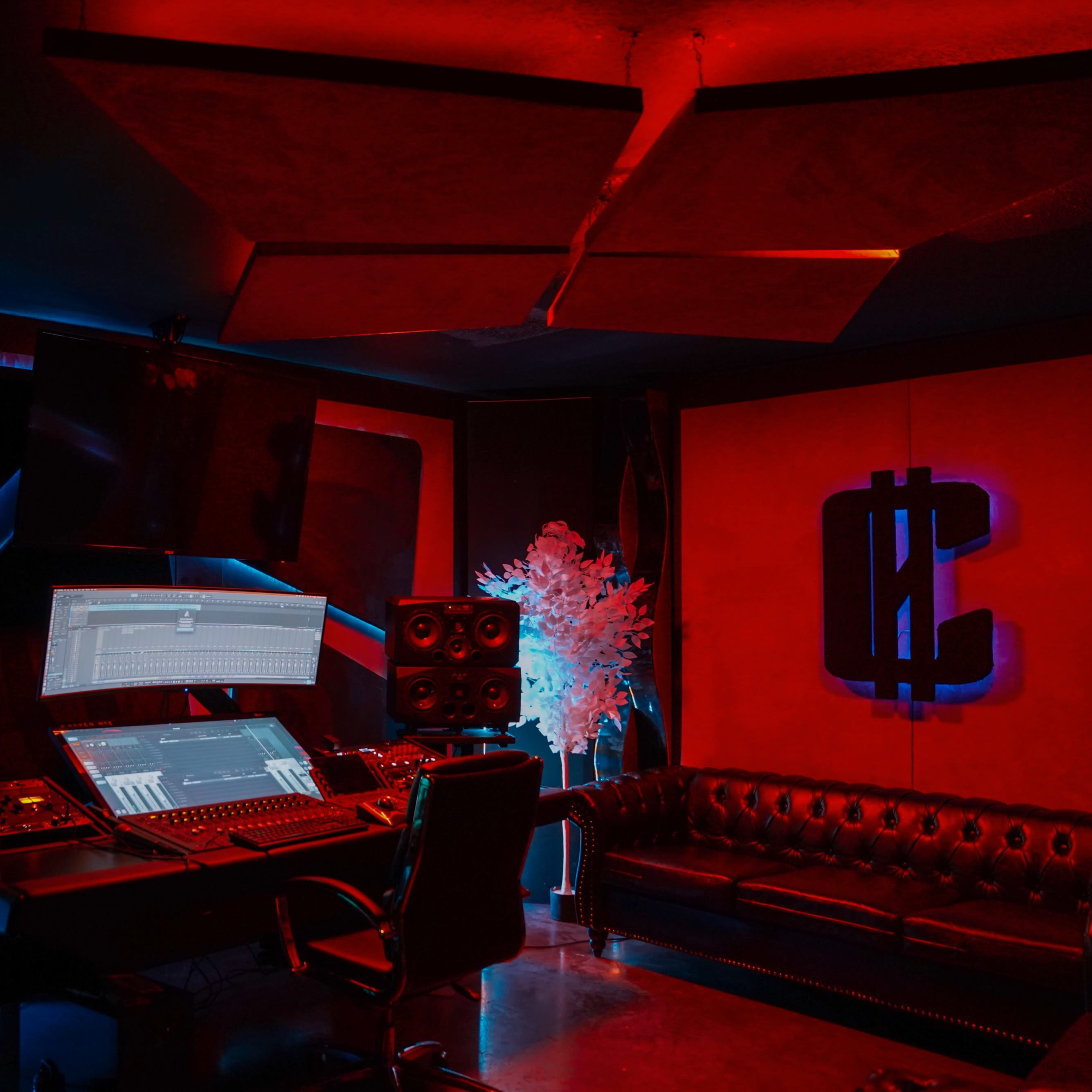 A music production studio featuring a large mixing desk, multiple speakers, and neon lighting accents.