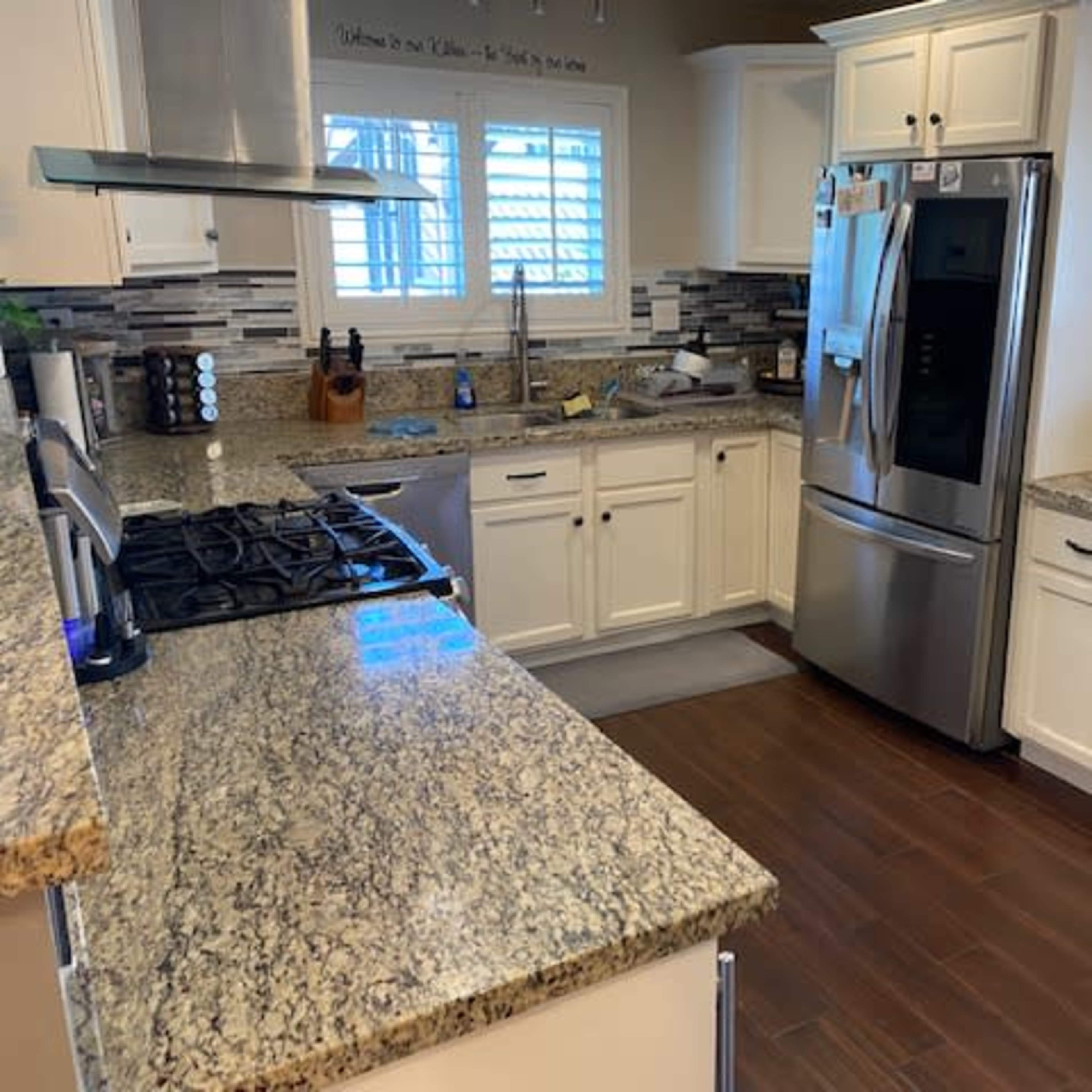 A modern kitchen features granite countertops, stainless steel appliances, and white cabinetry.