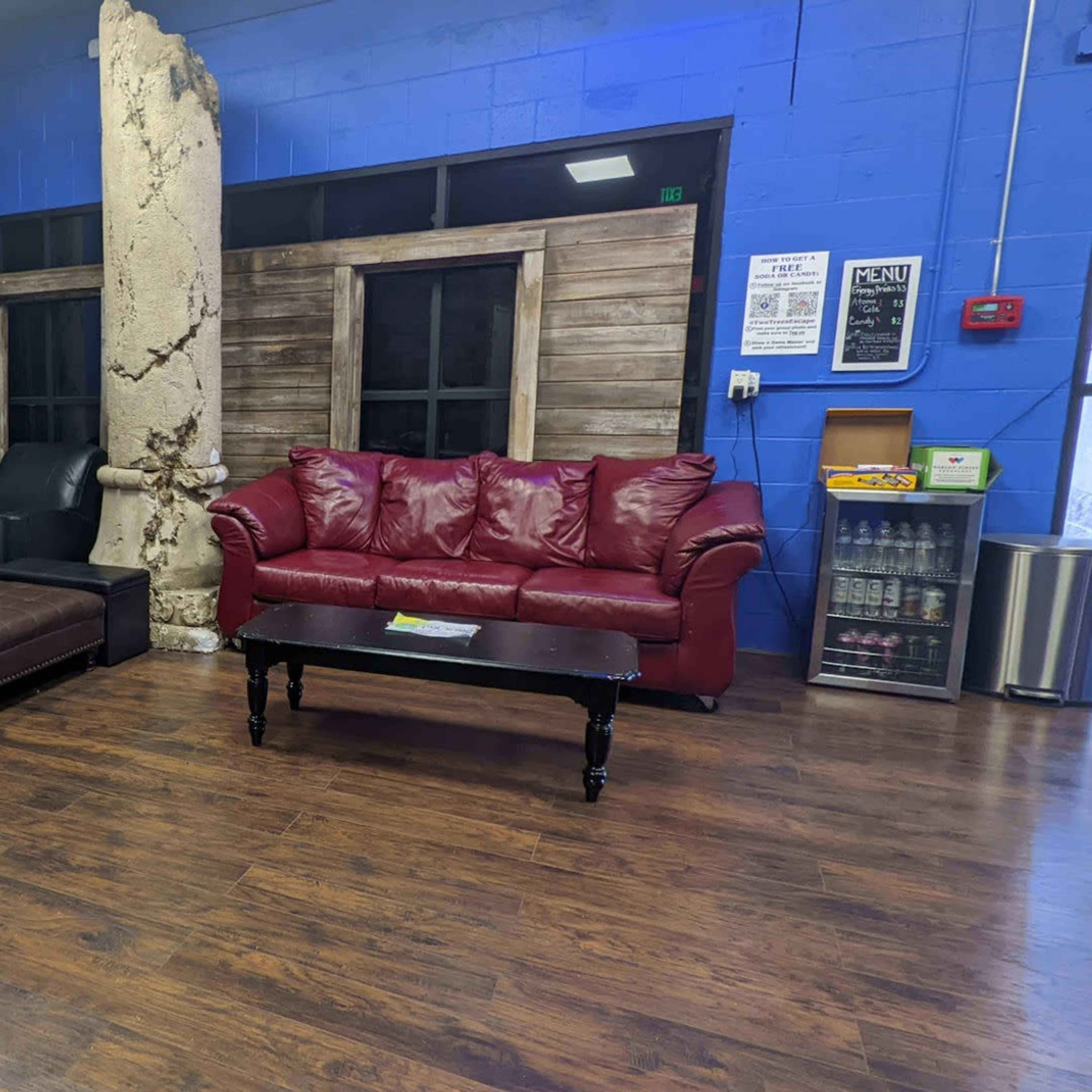 A waiting area with two large beige and burgundy sofas, a coffee table, and a backdrop of wooden panels and decorative columns in a blue and purple-painted room.