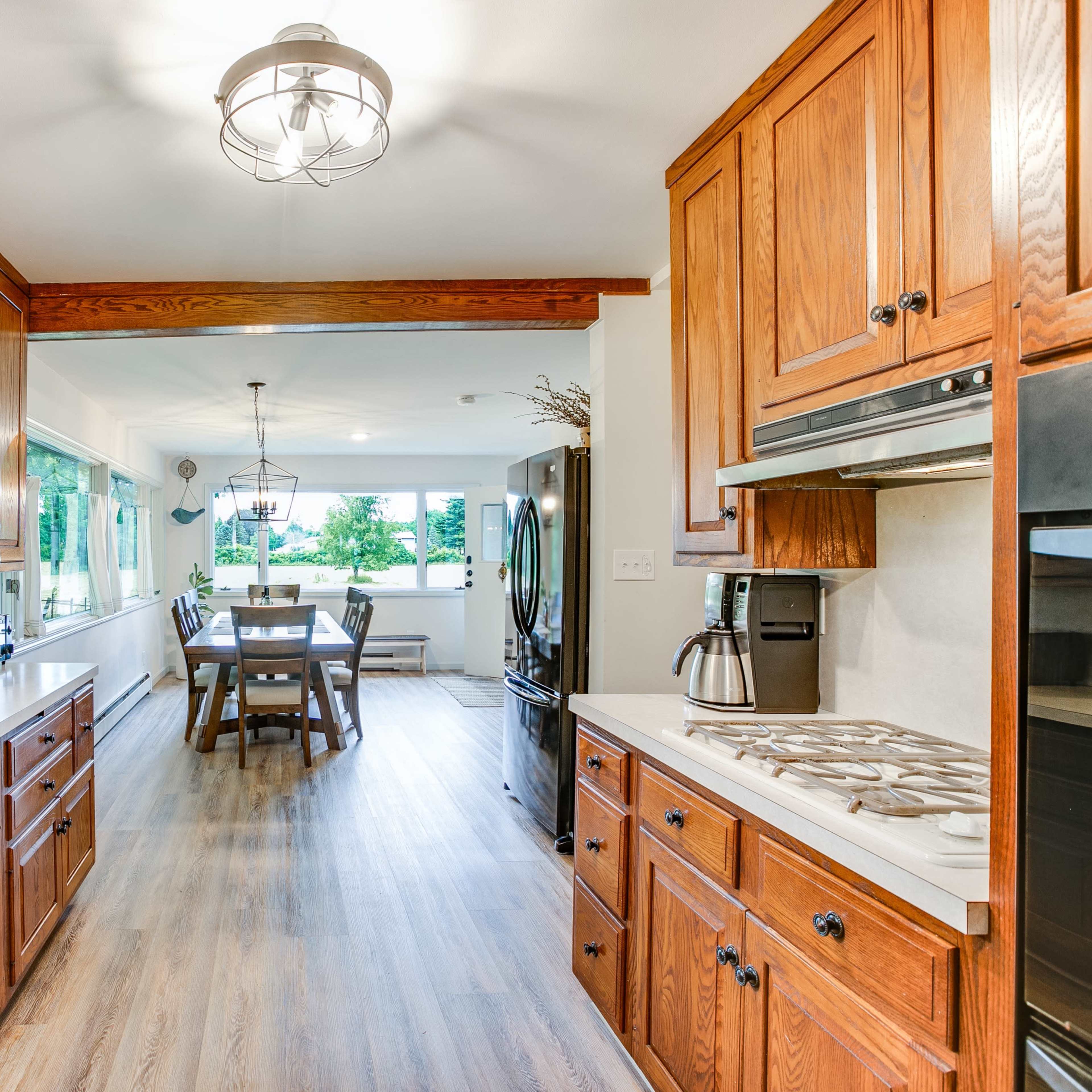 A modern kitchen with wooden cabinetry and a view of a dining area through an open passage.
