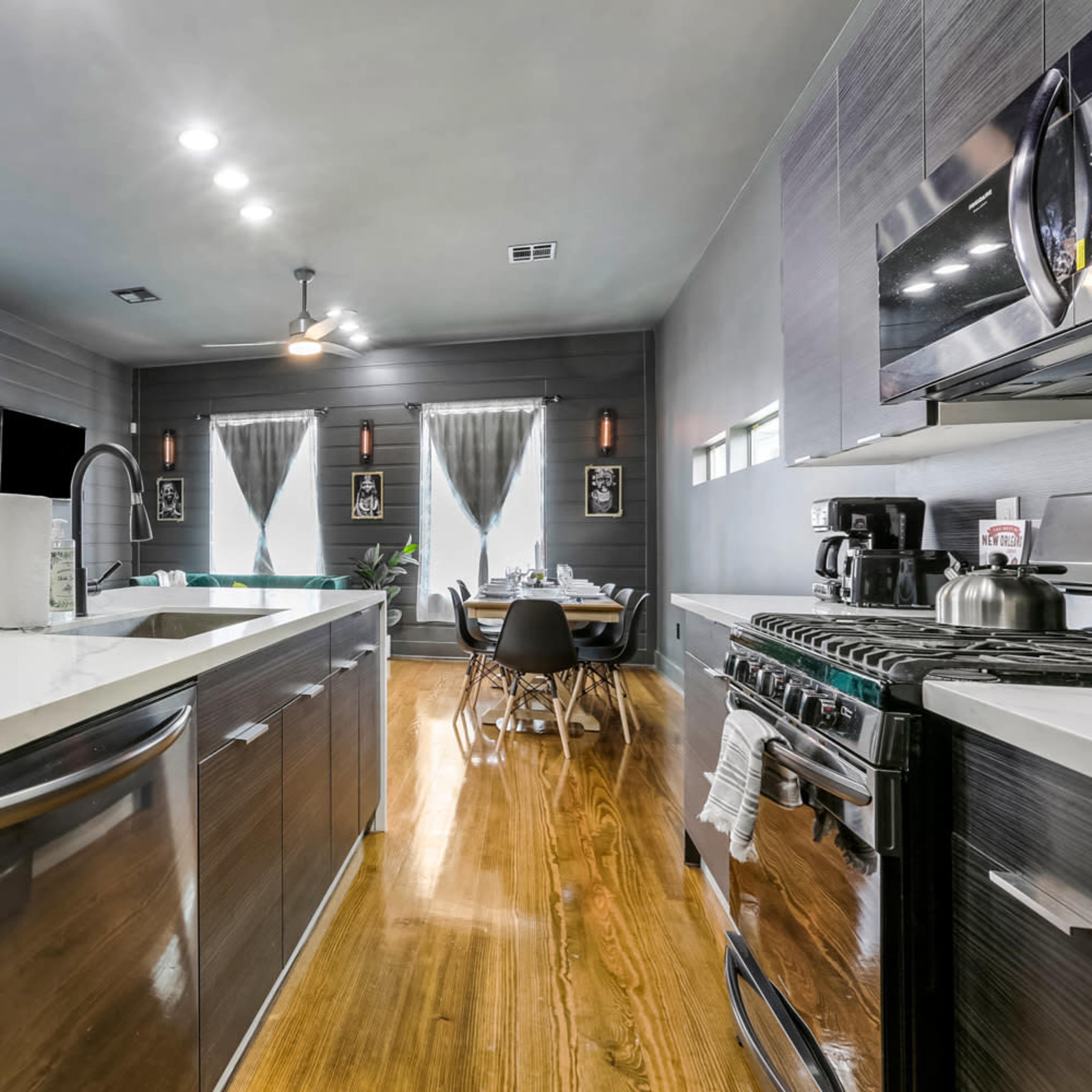 A modern kitchen features stainless steel appliances, a large island with a white countertop, and an adjoining dining area.