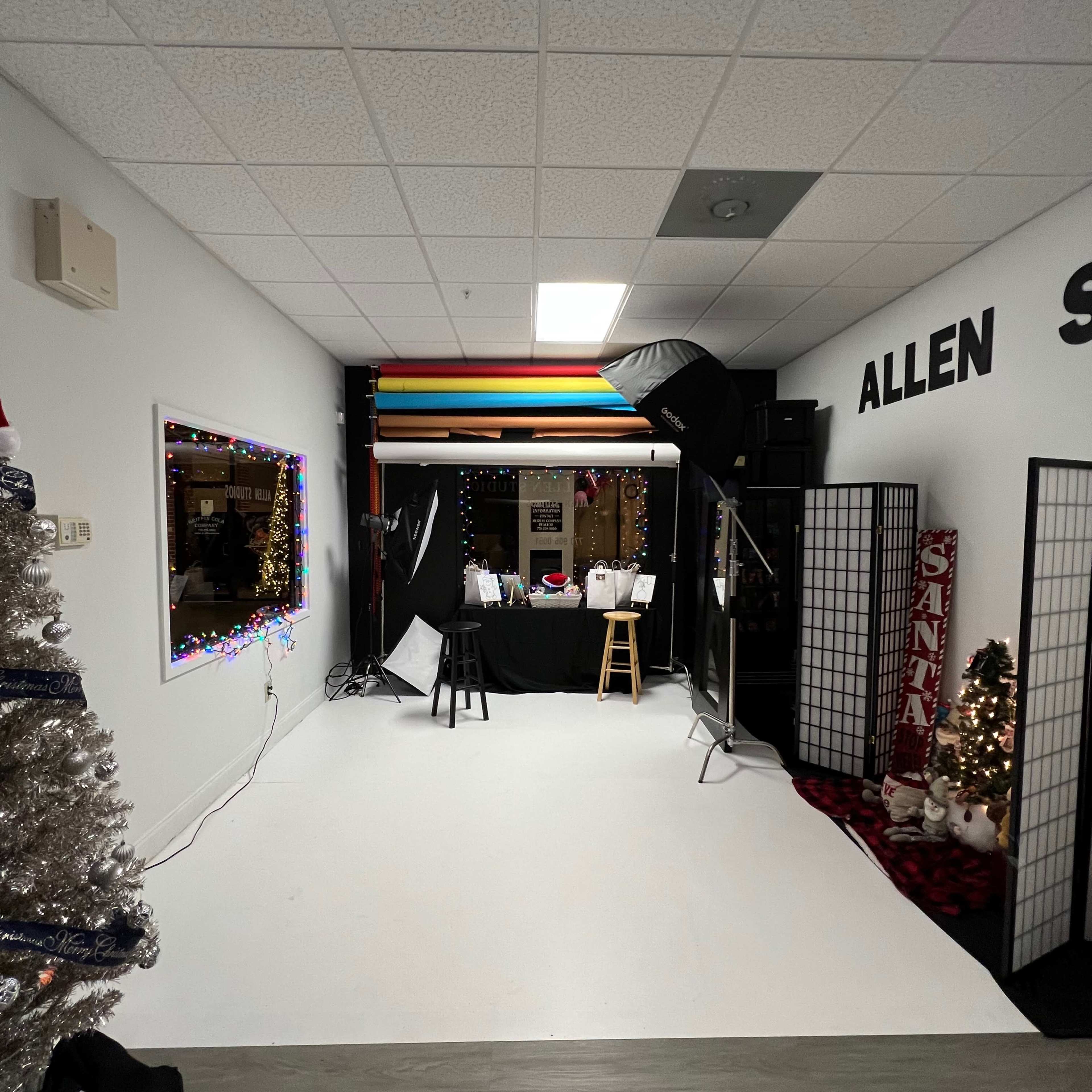A photography studio with bright backdrops, a Christmas tree in the corner, and various props set up for a photo session.