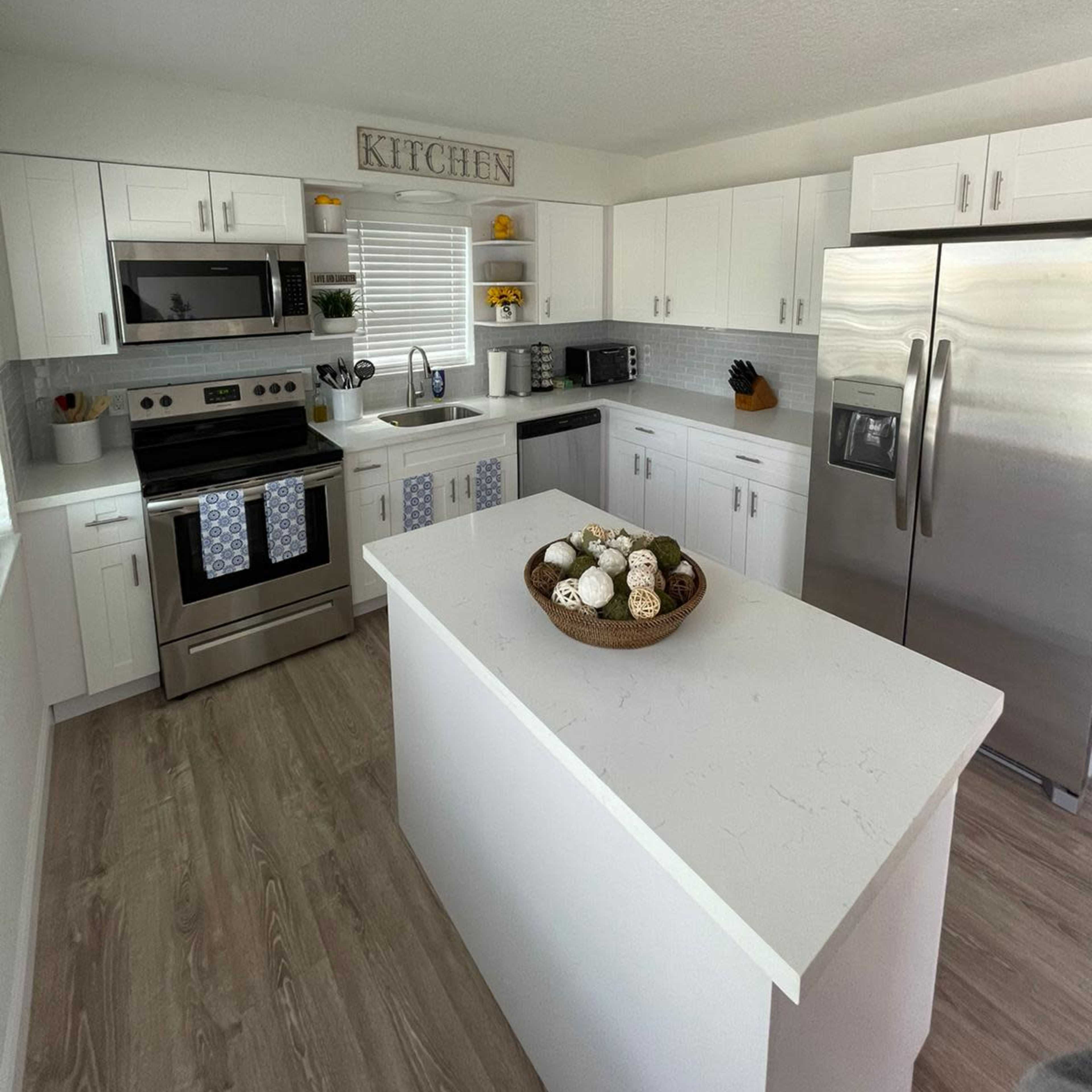 The kitchen features white cabinetry, stainless steel appliances, and a central island decorated with a bowl of decorative items.