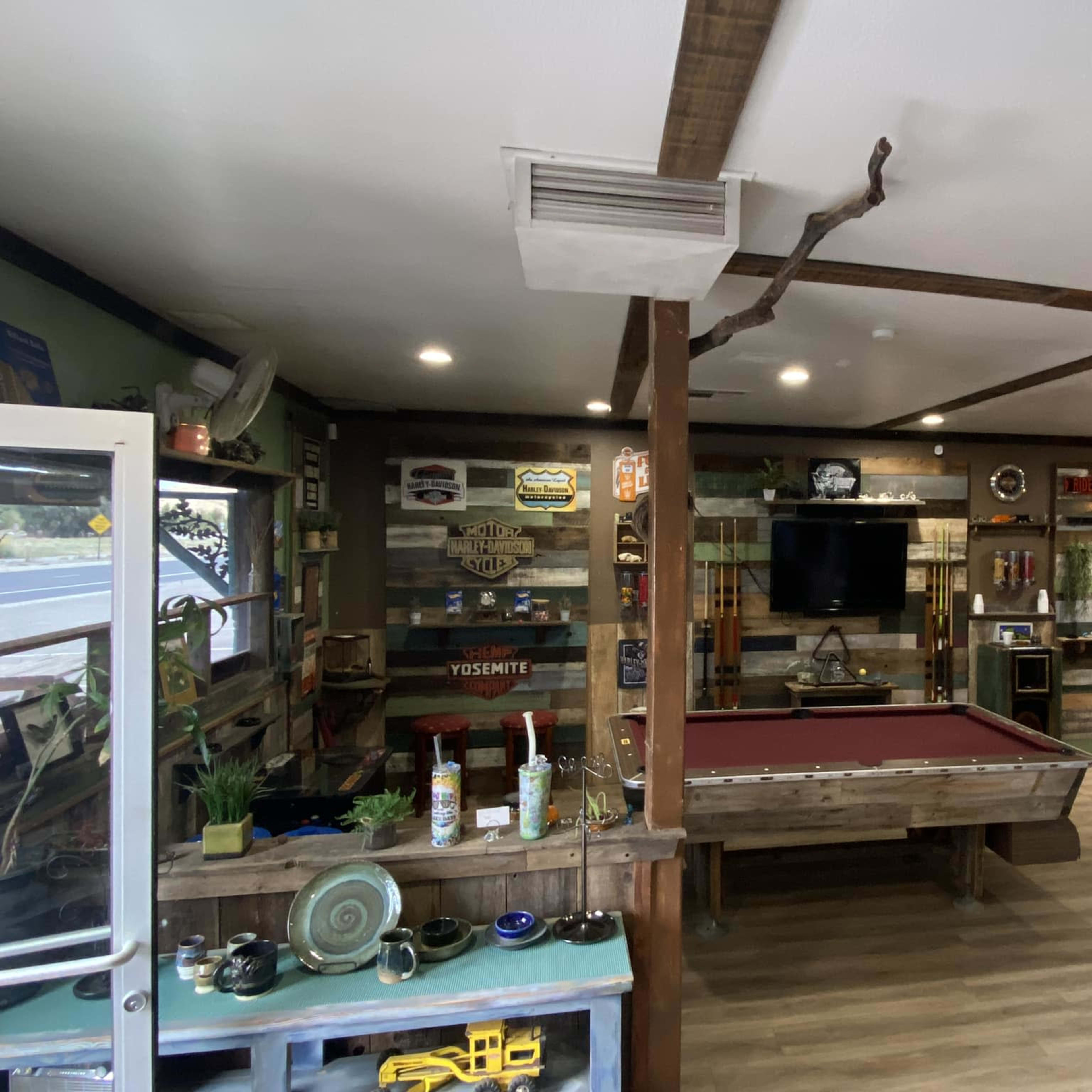 The interior of a recreational room features a pool table, a wall-mounted TV, and various vintage signs and decor.