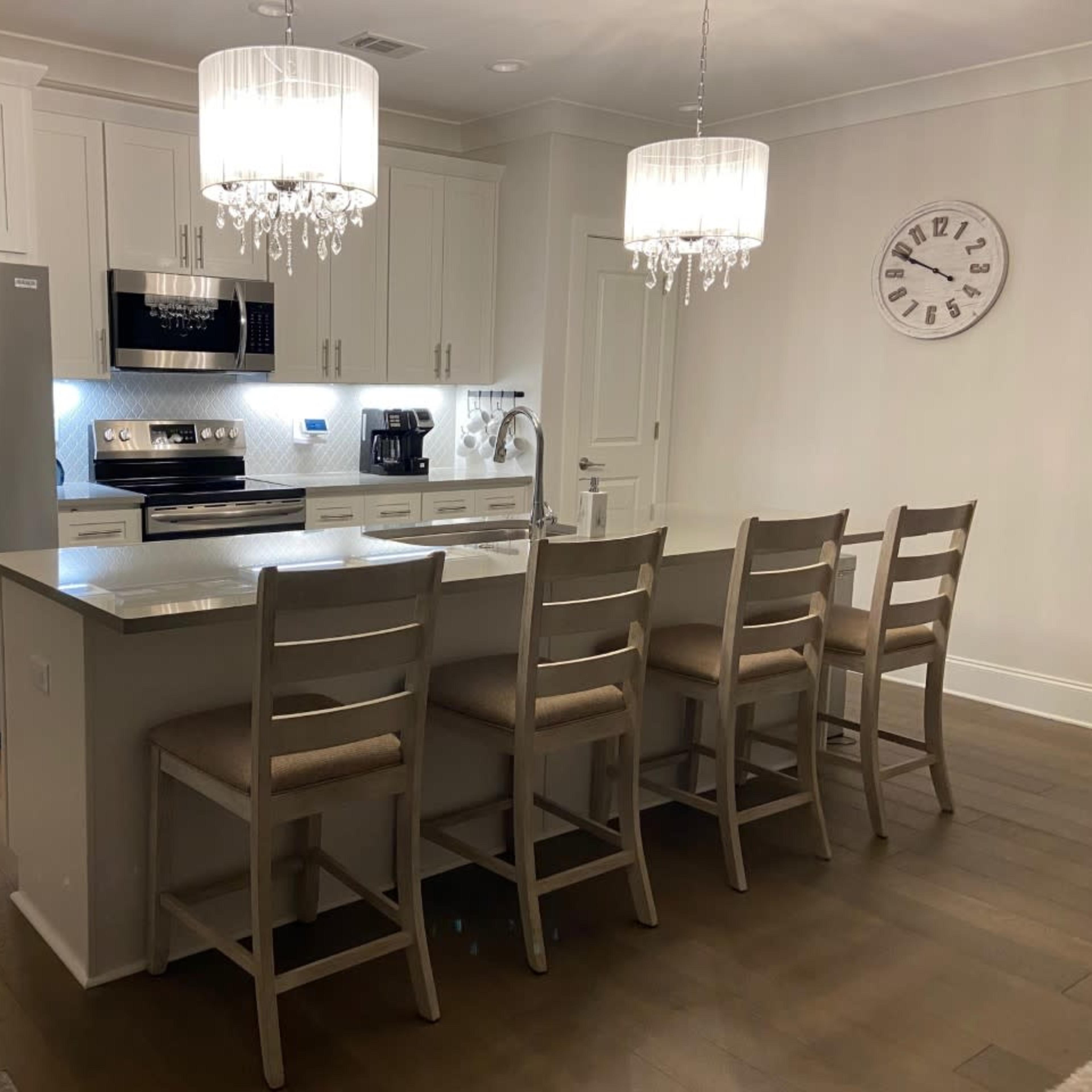 A modern kitchen with white cabinetry, stainless steel appliances, and a large island with seating for six.
