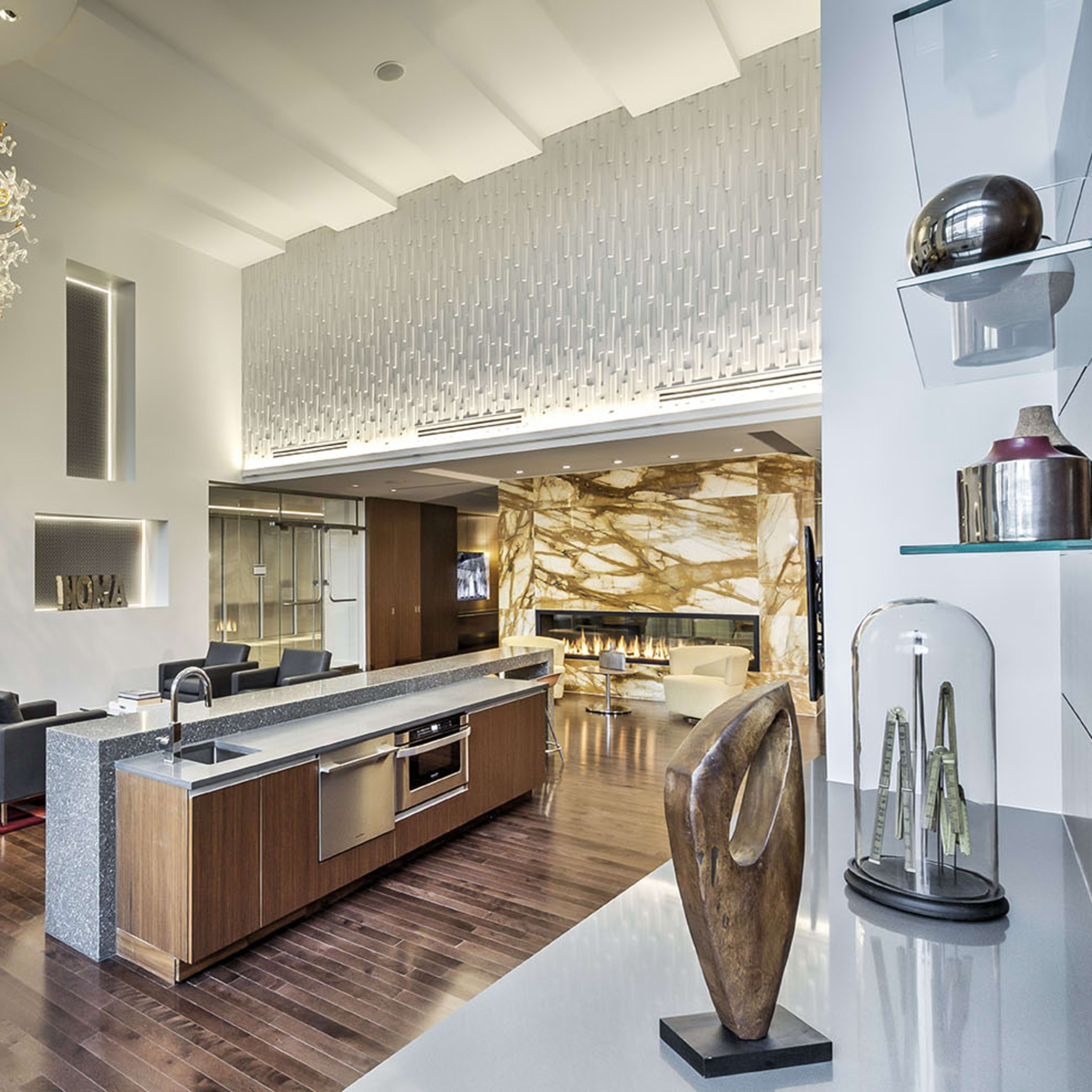 A modern lounge area featuring a large kitchen island, stylish furniture, and an eye-catching chandelier.