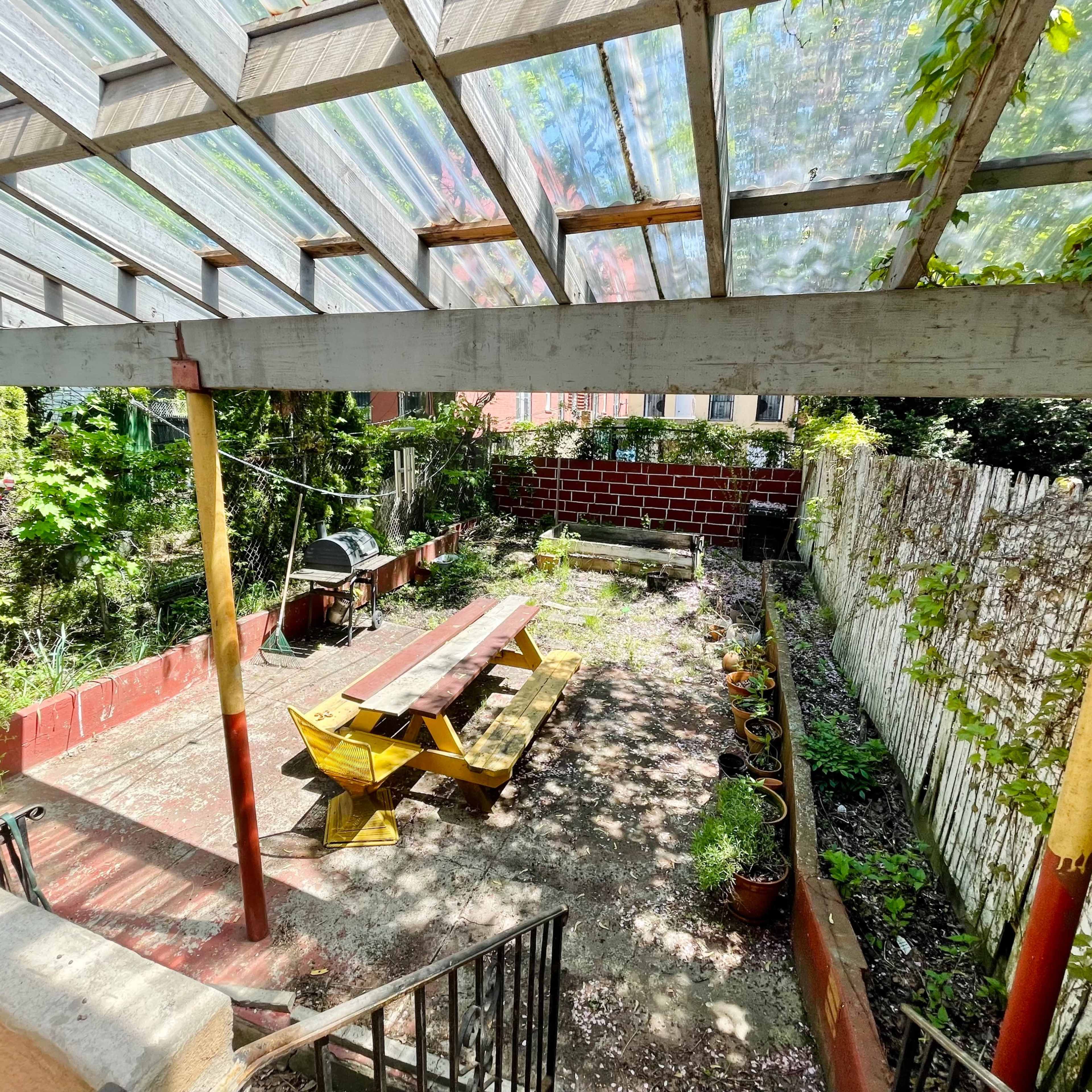 A dining table is set with various plates, a bouquet of flowers, and a spread of food in a rustic room with peeling walls and framed artworks.