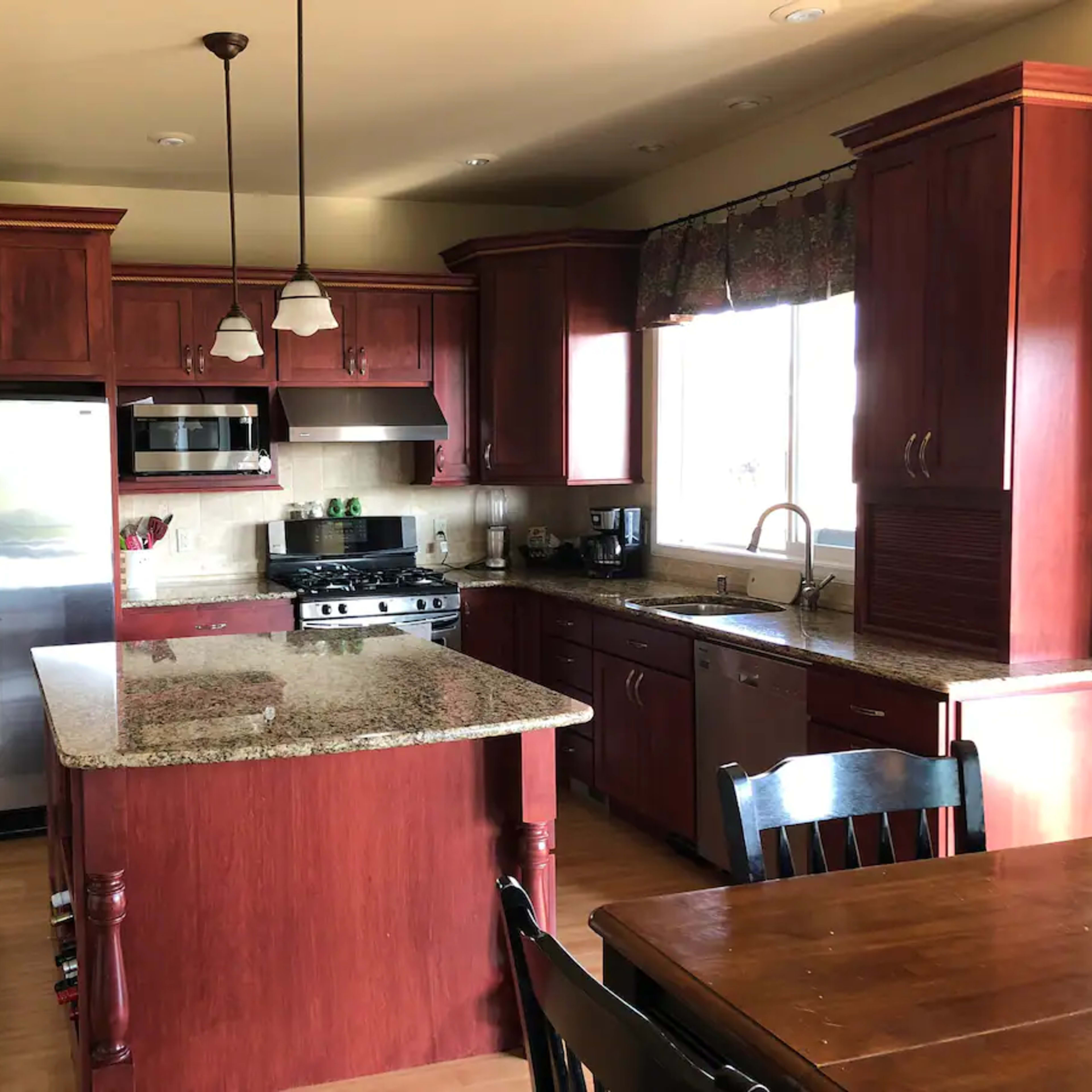 A kitchen with wooden cabinets, granite countertops, and stainless steel appliances.