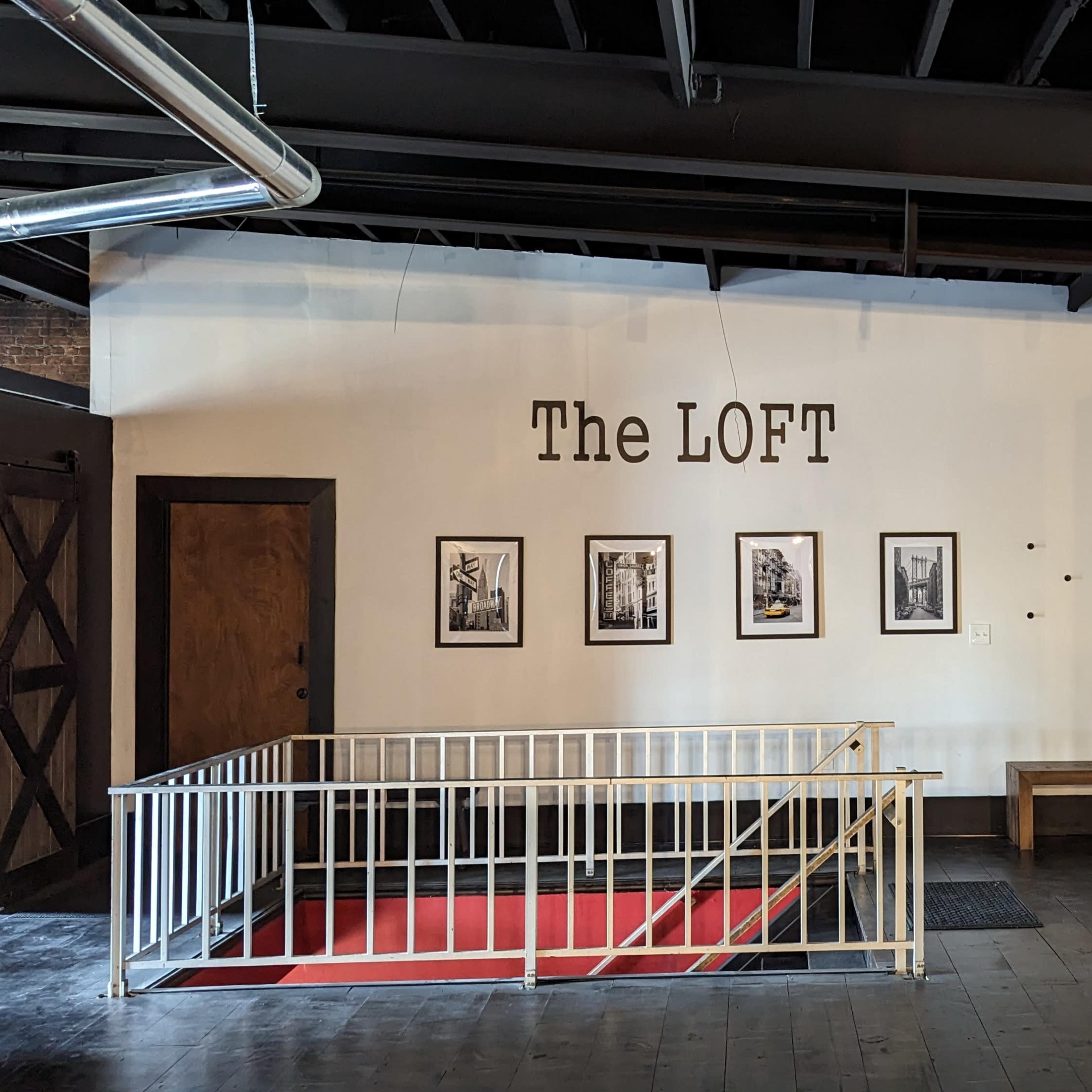 An interior space labeled "The LOFT," featuring a wall with four framed black-and-white photographs and a colorful graffiti mural on the adjacent wall.