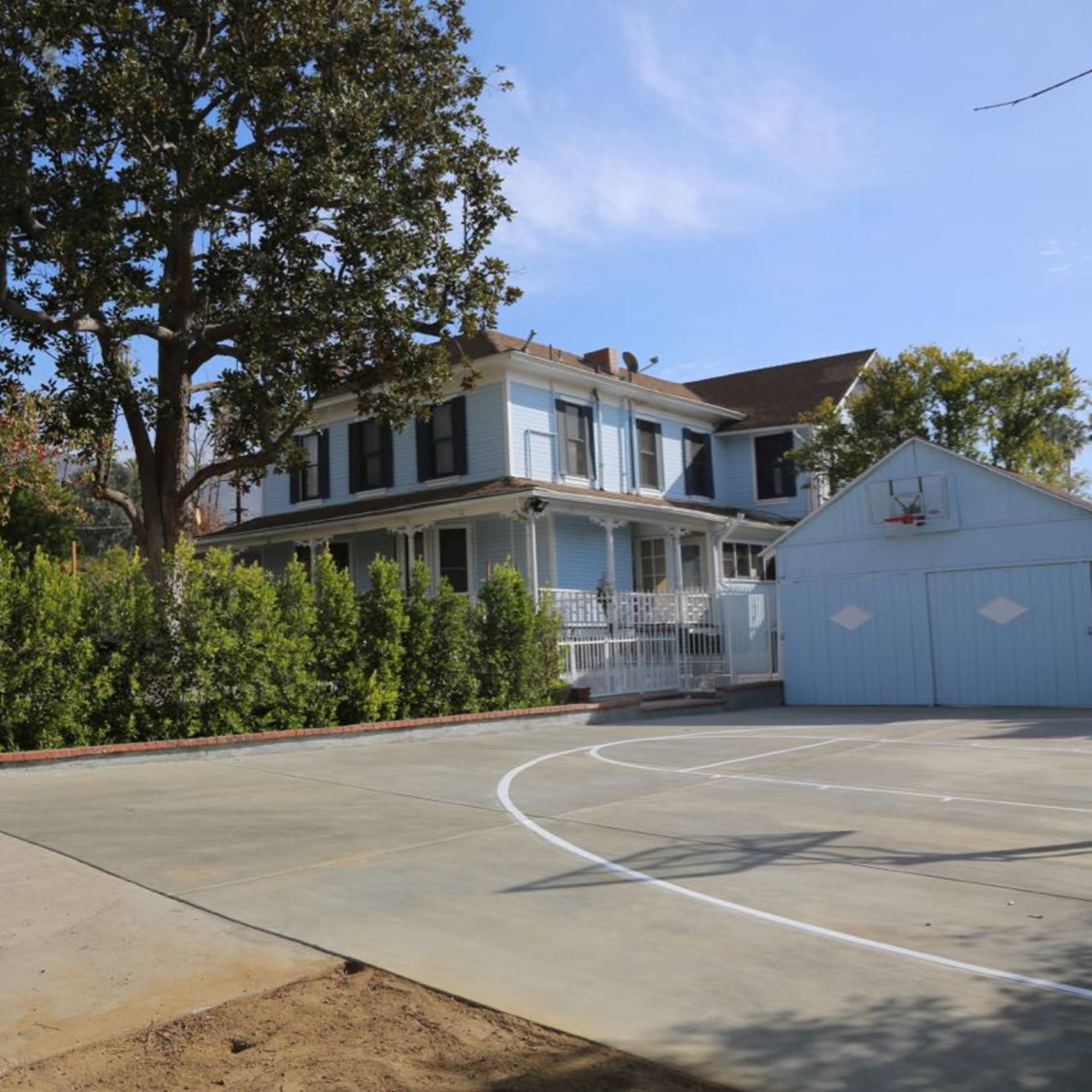 A residential property with a large house, a separate garage, and a concrete basketball court.