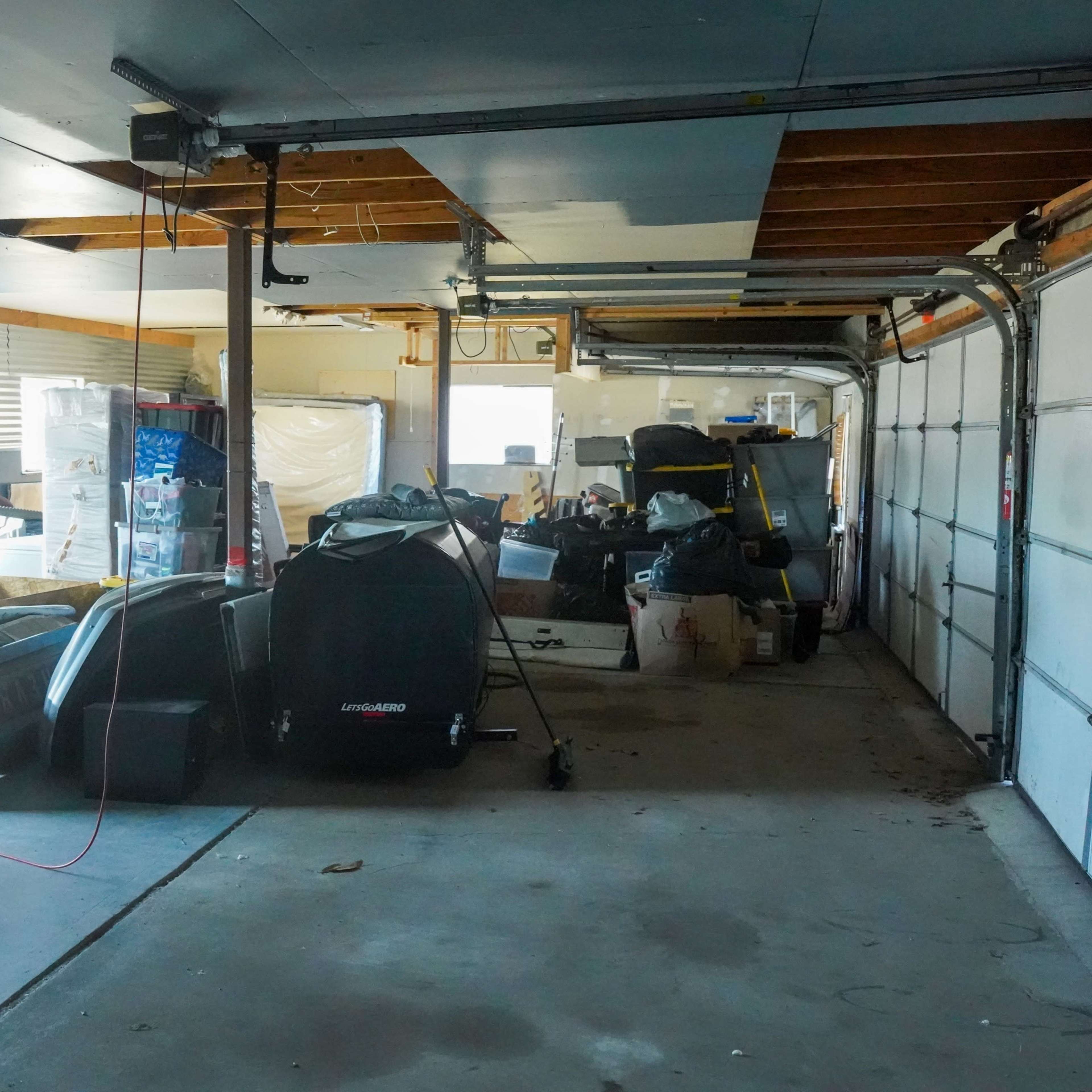 A cluttered garage filled with various items, including furniture, boxes, and tools.