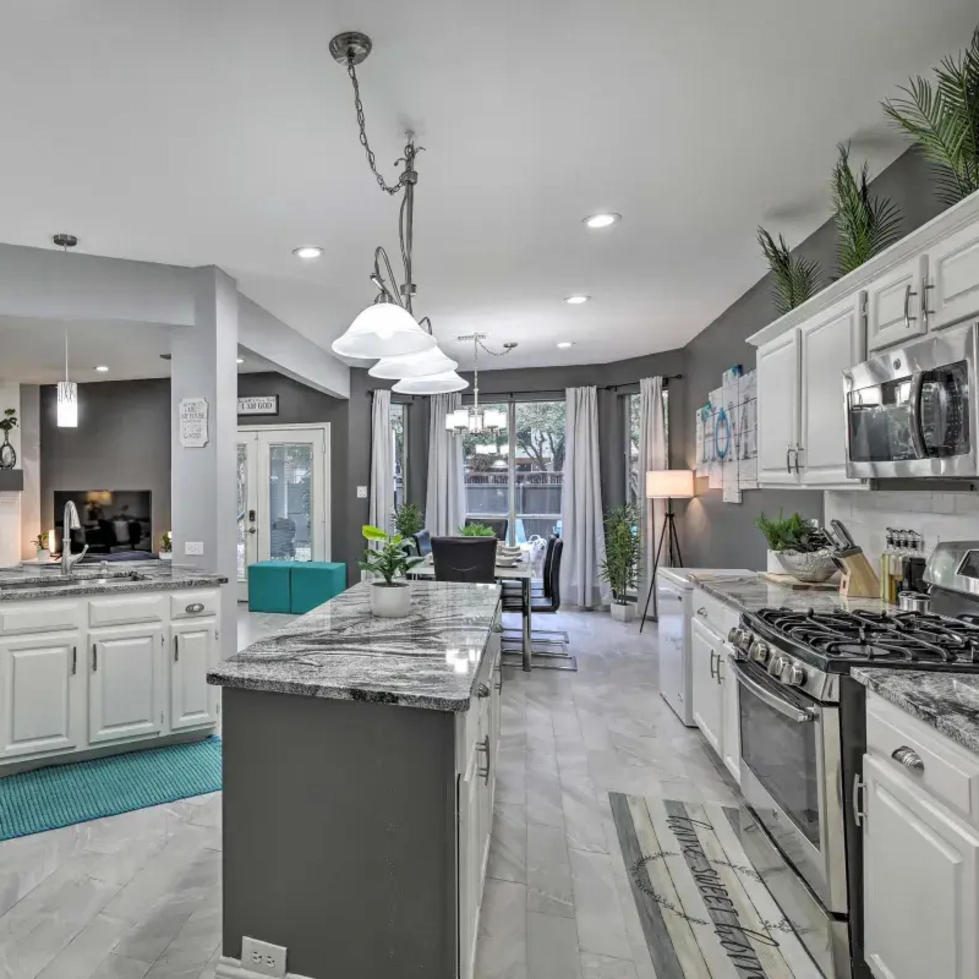 The kitchen features white cabinets, granite countertops, stainless steel appliances, and a spacious layout that connects to a dining area.