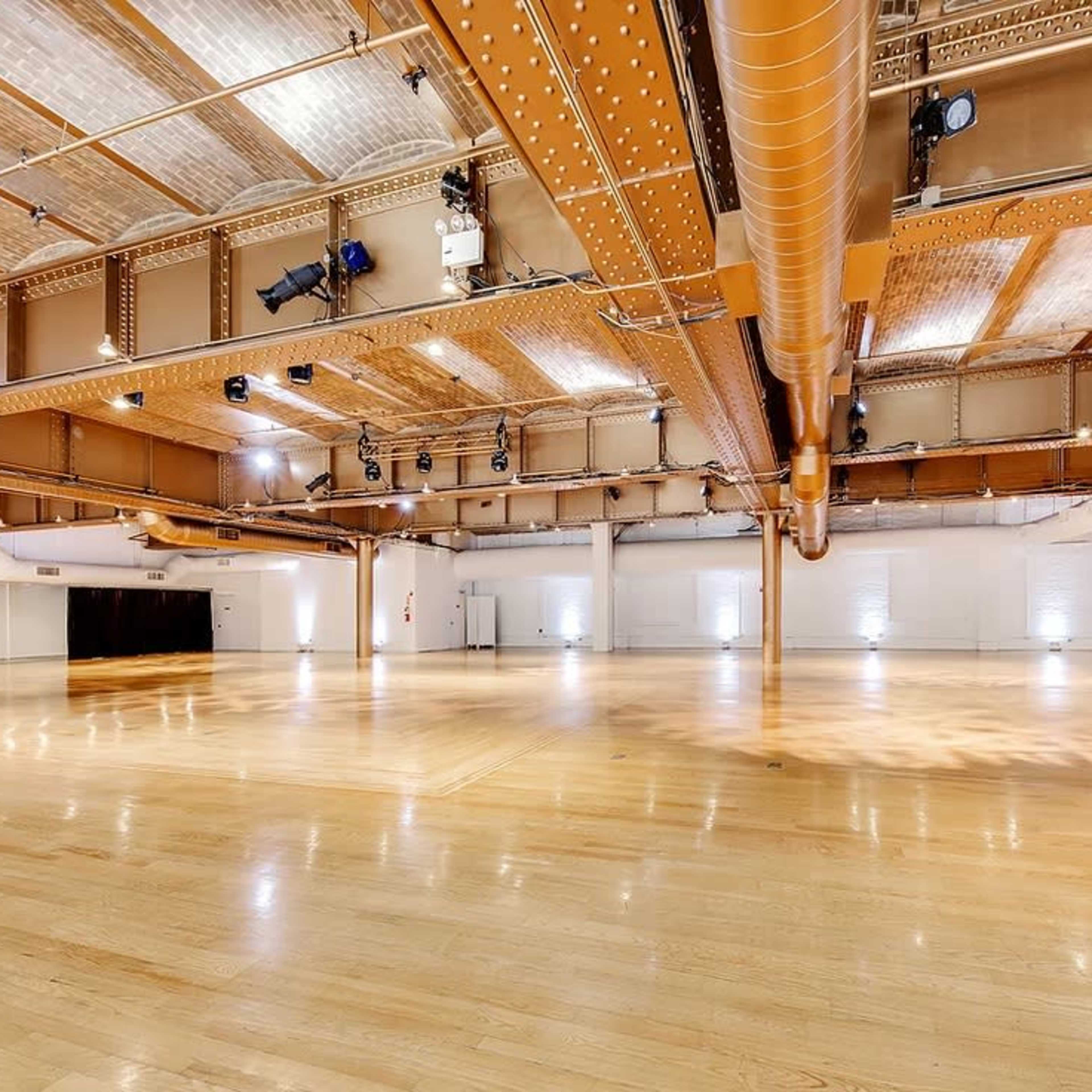A spacious, well-lit interior with wooden flooring and exposed metal beams.