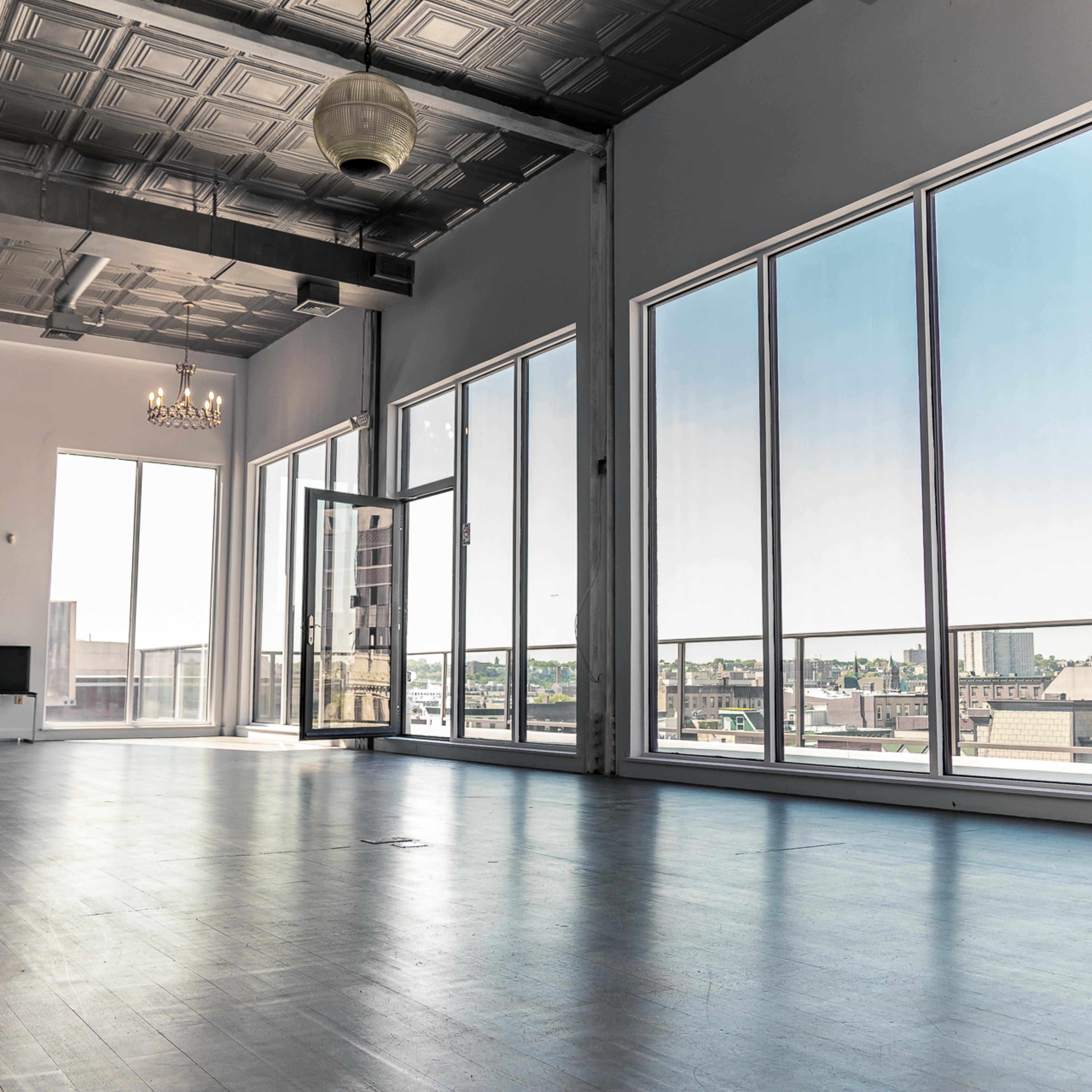 A large, empty room with large windows offering a view of the city skyline.