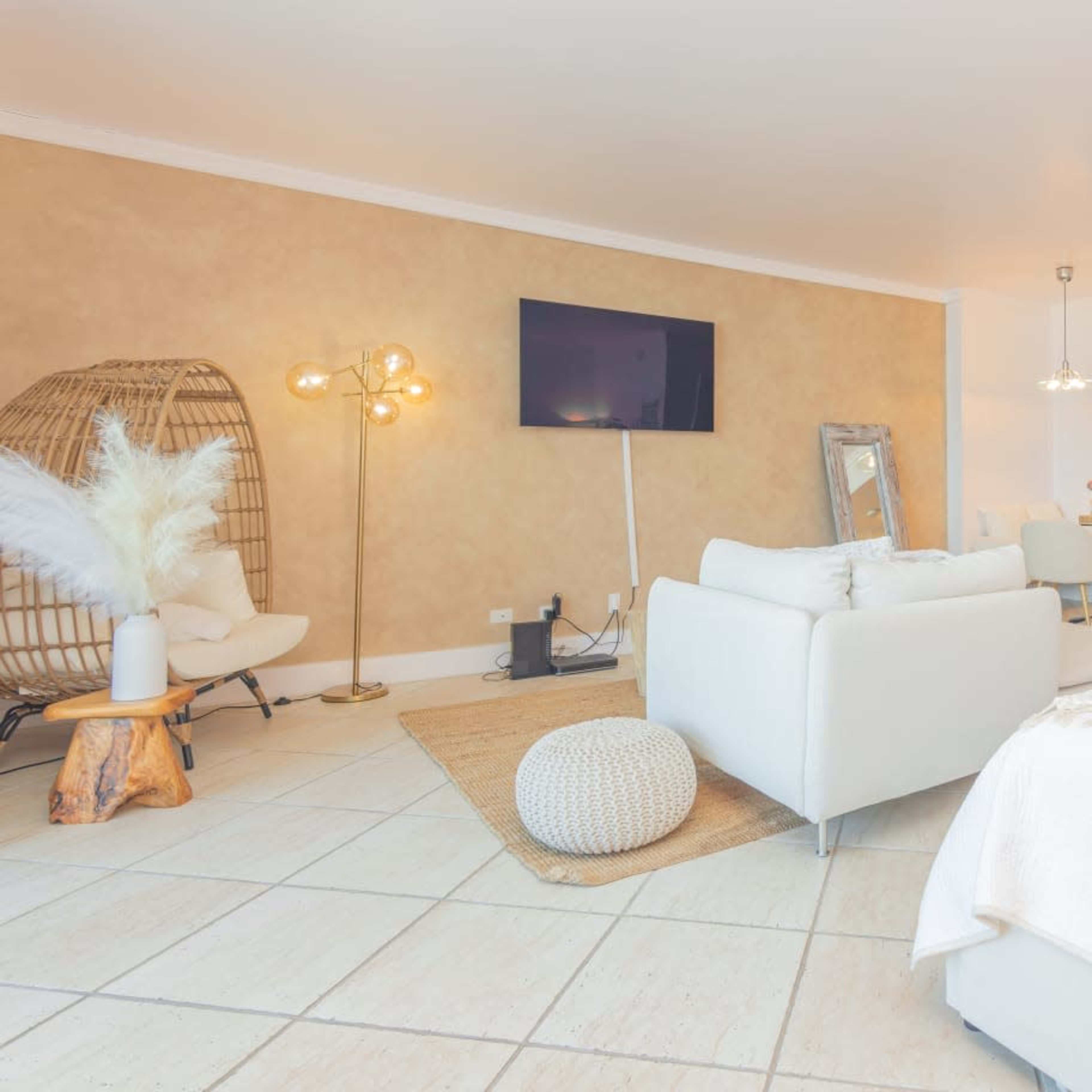 A modern, well-lit open living space featuring a cozy seating area, a kitchen with stainless steel appliances, and a decorative light fixture.