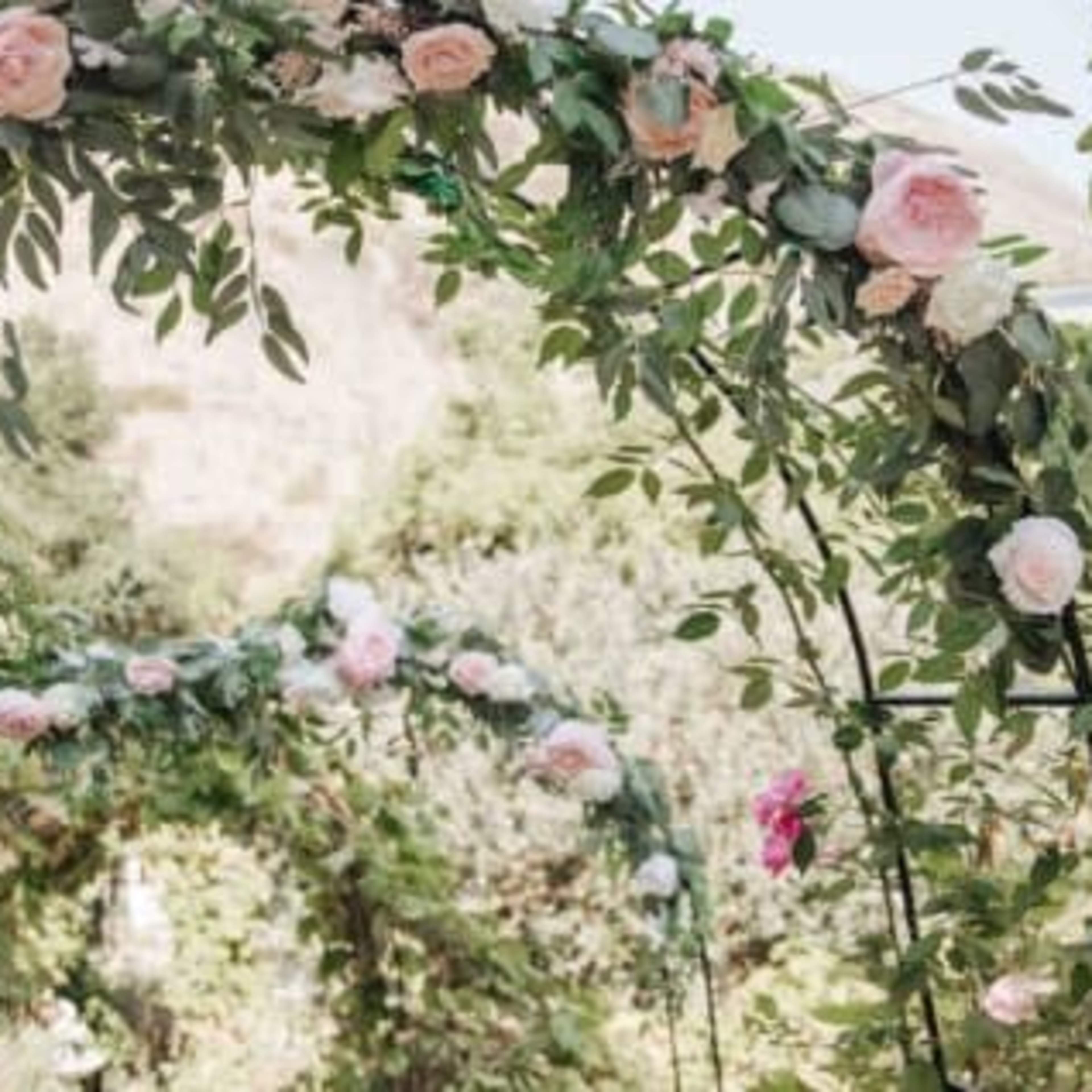 A garden pathway adorned with floral arches made of roses and greenery.