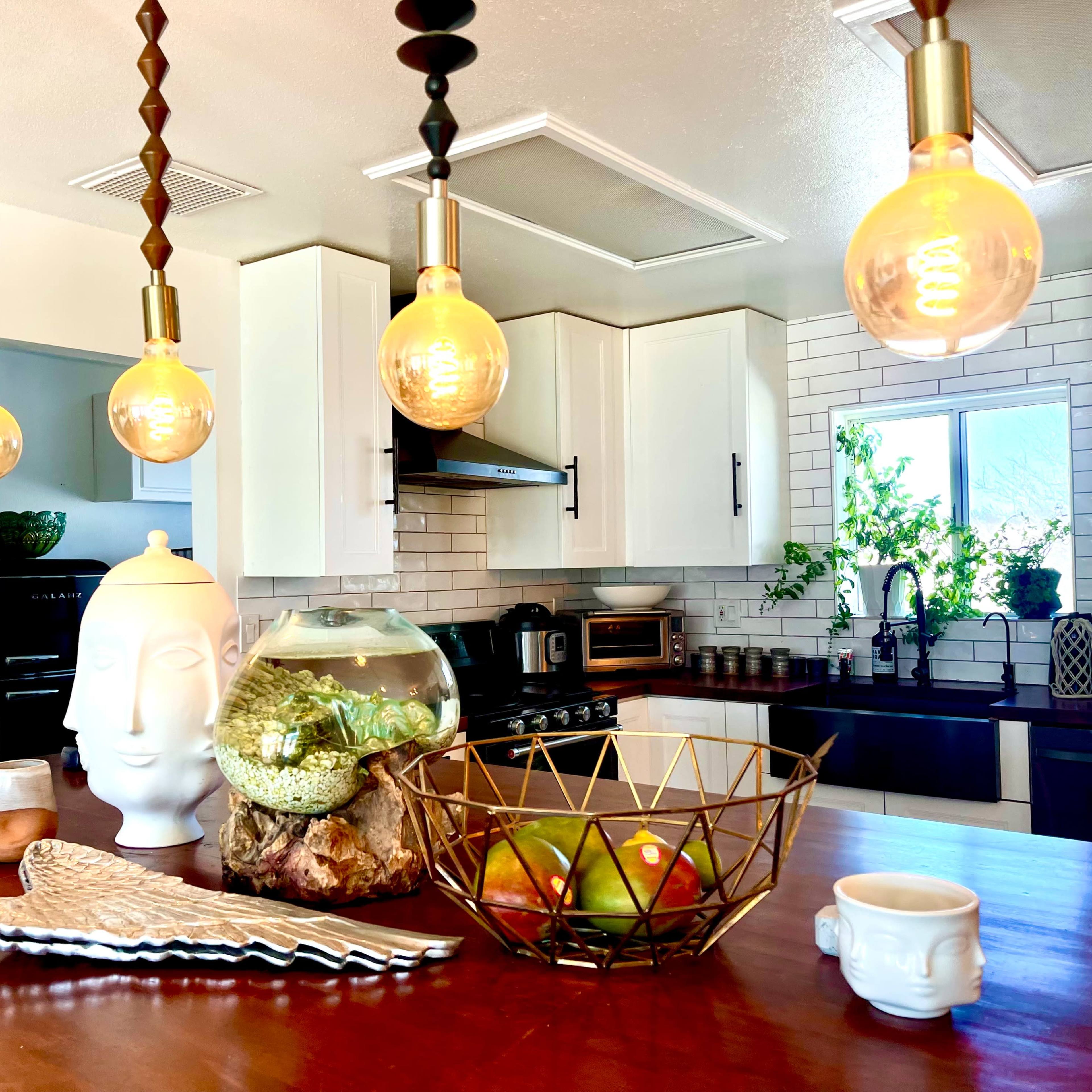 A contemporary kitchen with a wooden island, decorative elements including a vase and a fishbowl, and pendant lighting above the countertop.