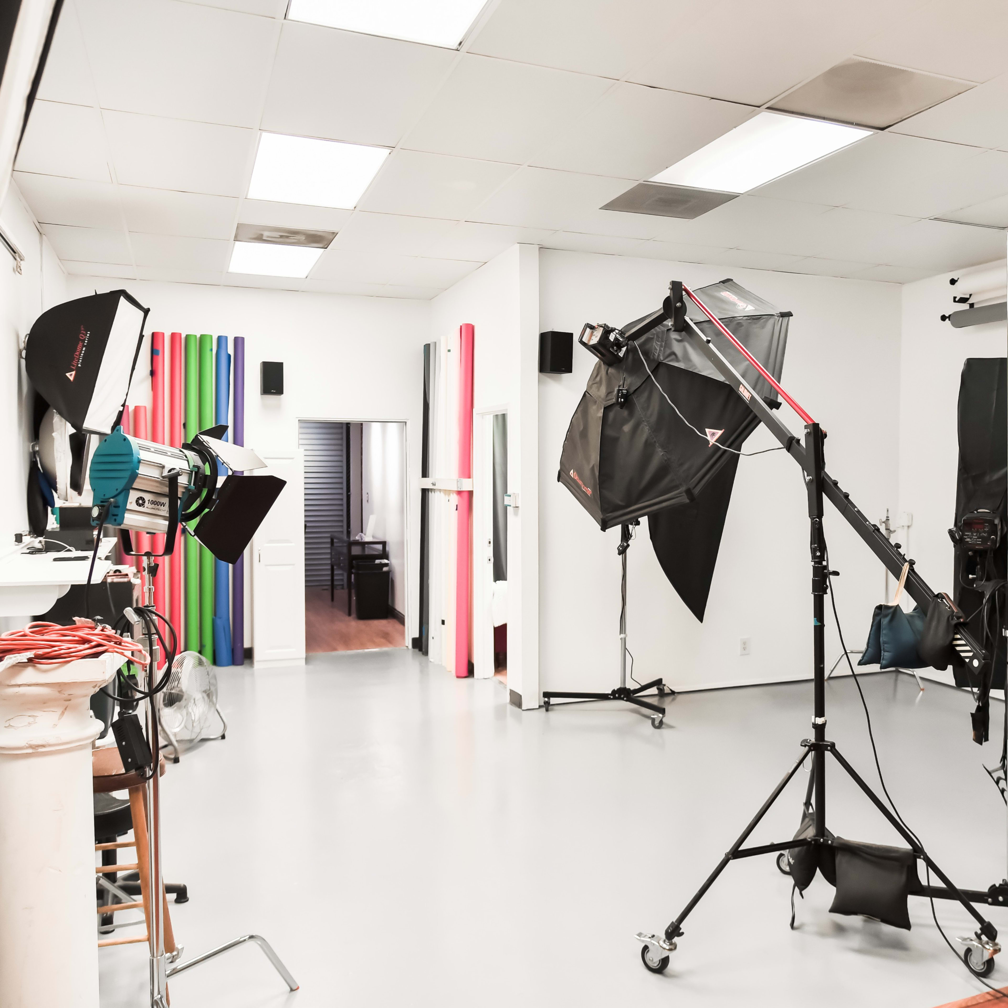 A photography studio equipped with lighting setups, backdrops, and a camera on a tripod.