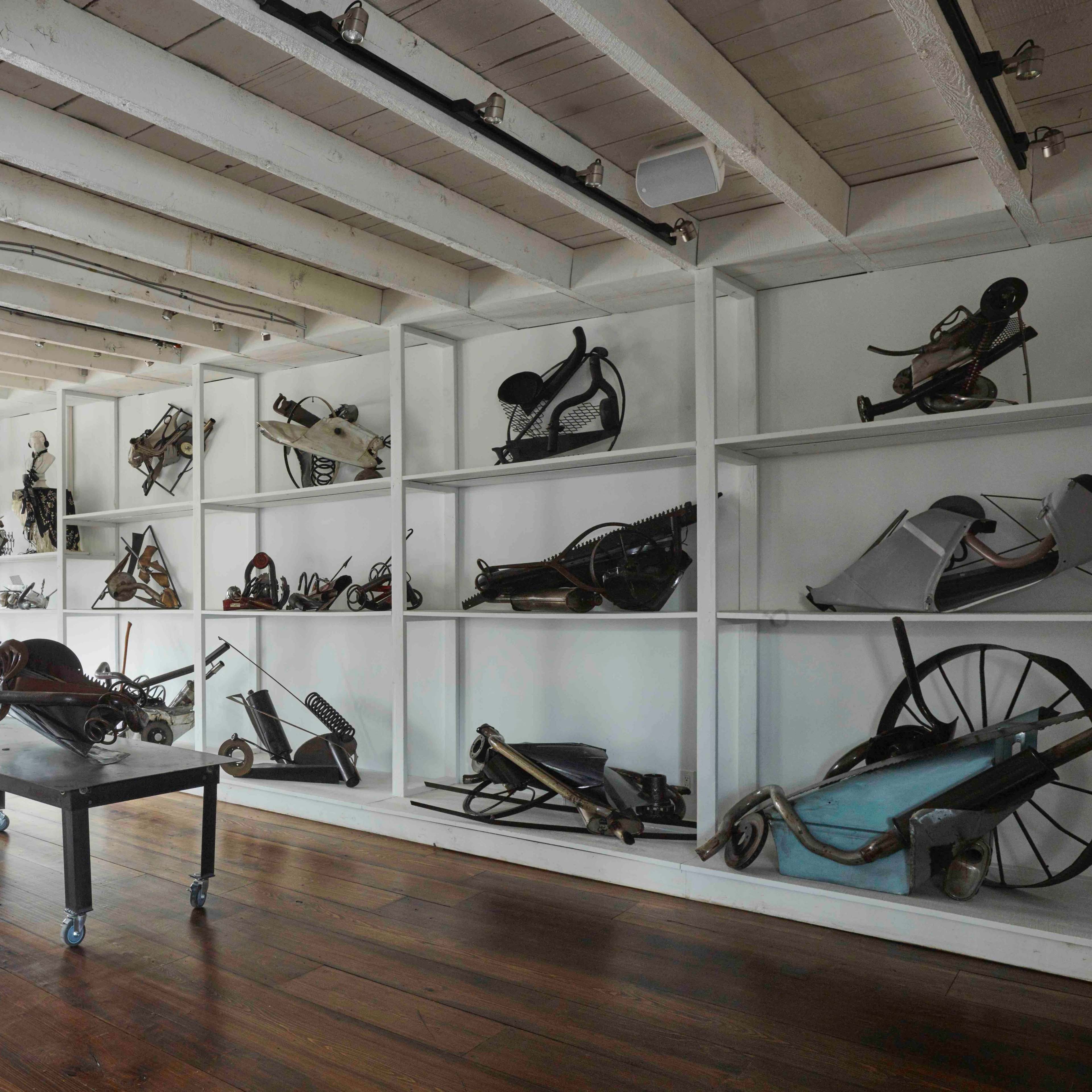 A spacious room with wooden floors and white shelves displaying various antique industrial tools and equipment.