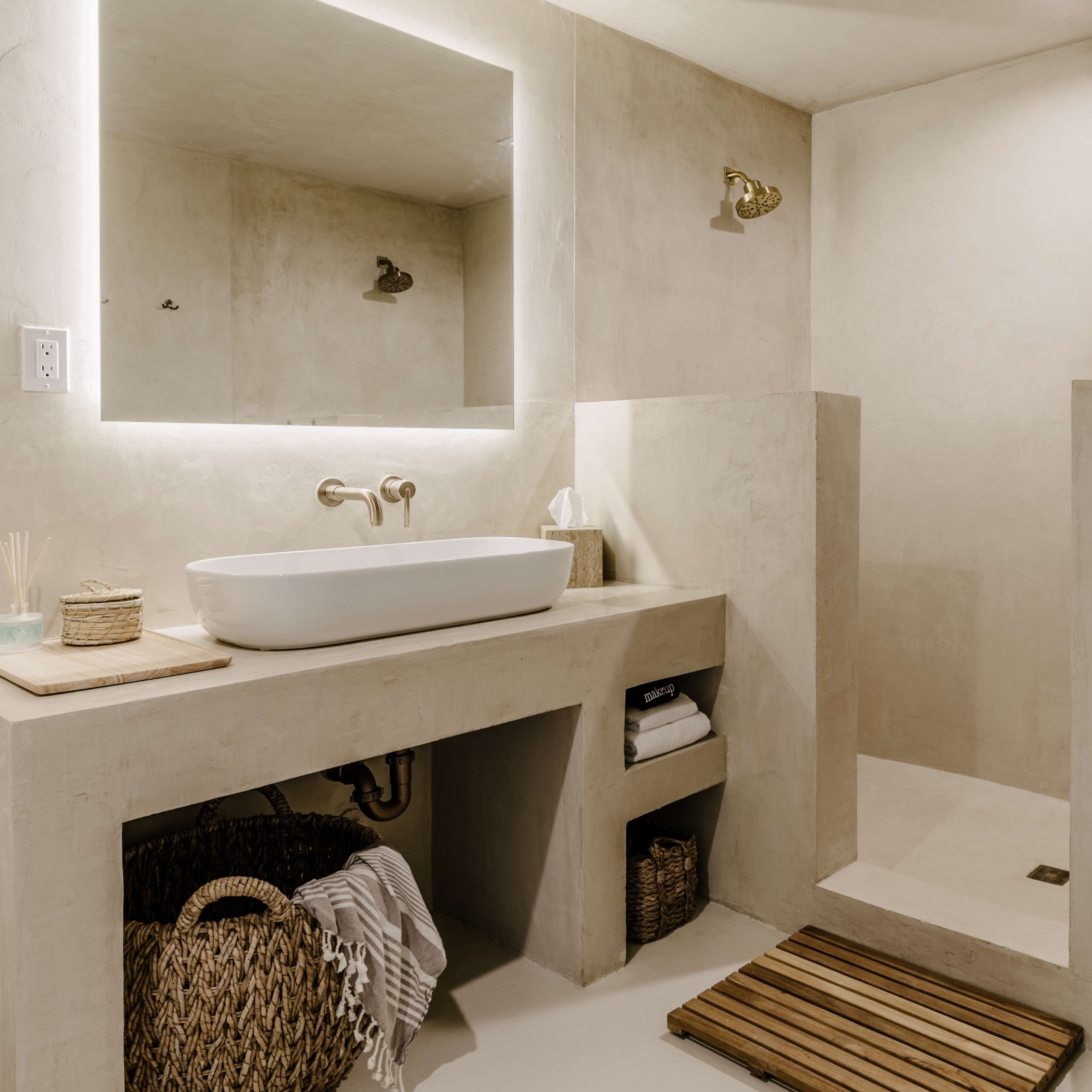 A minimalist bathroom with a large mirror, a vessel sink on a countertop, a spacious shower area, and textured walls.