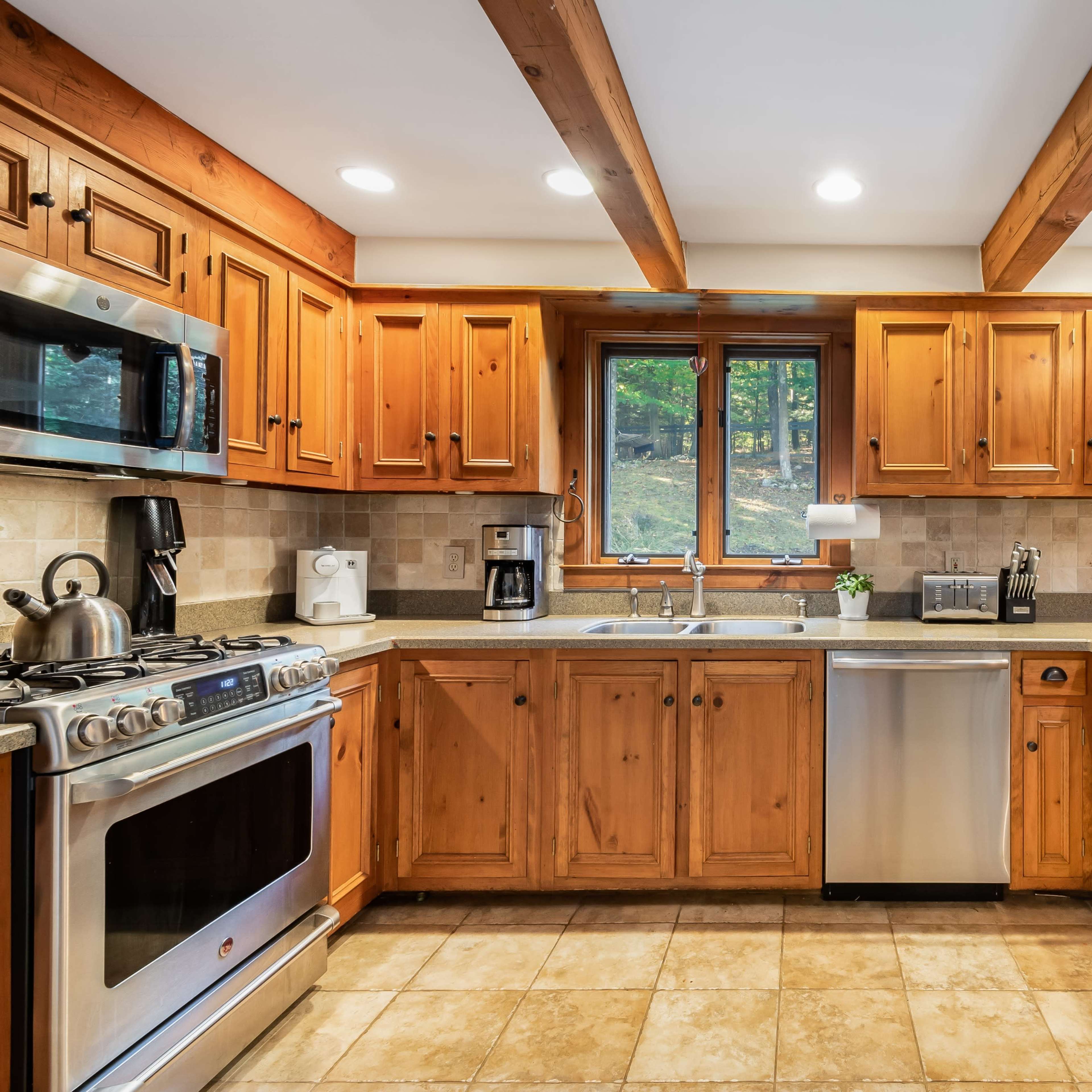 The kitchen features wooden cabinets, a stainless steel sink, and modern appliances with a view of the outdoors through a large window.