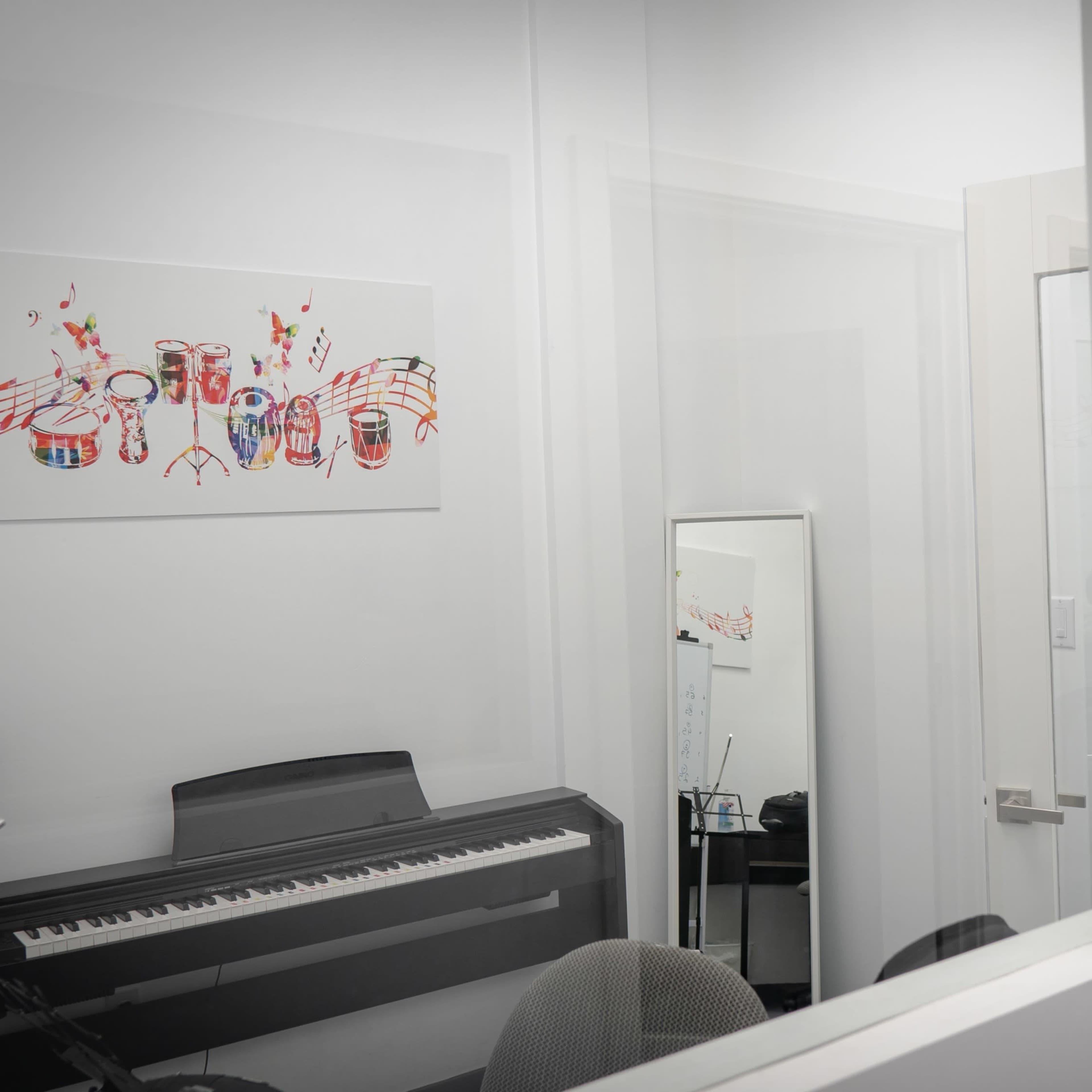 A piano is visible inside a small room, with a mirror and a chair positioned nearby, and sheet music artwork hanging on the wall.