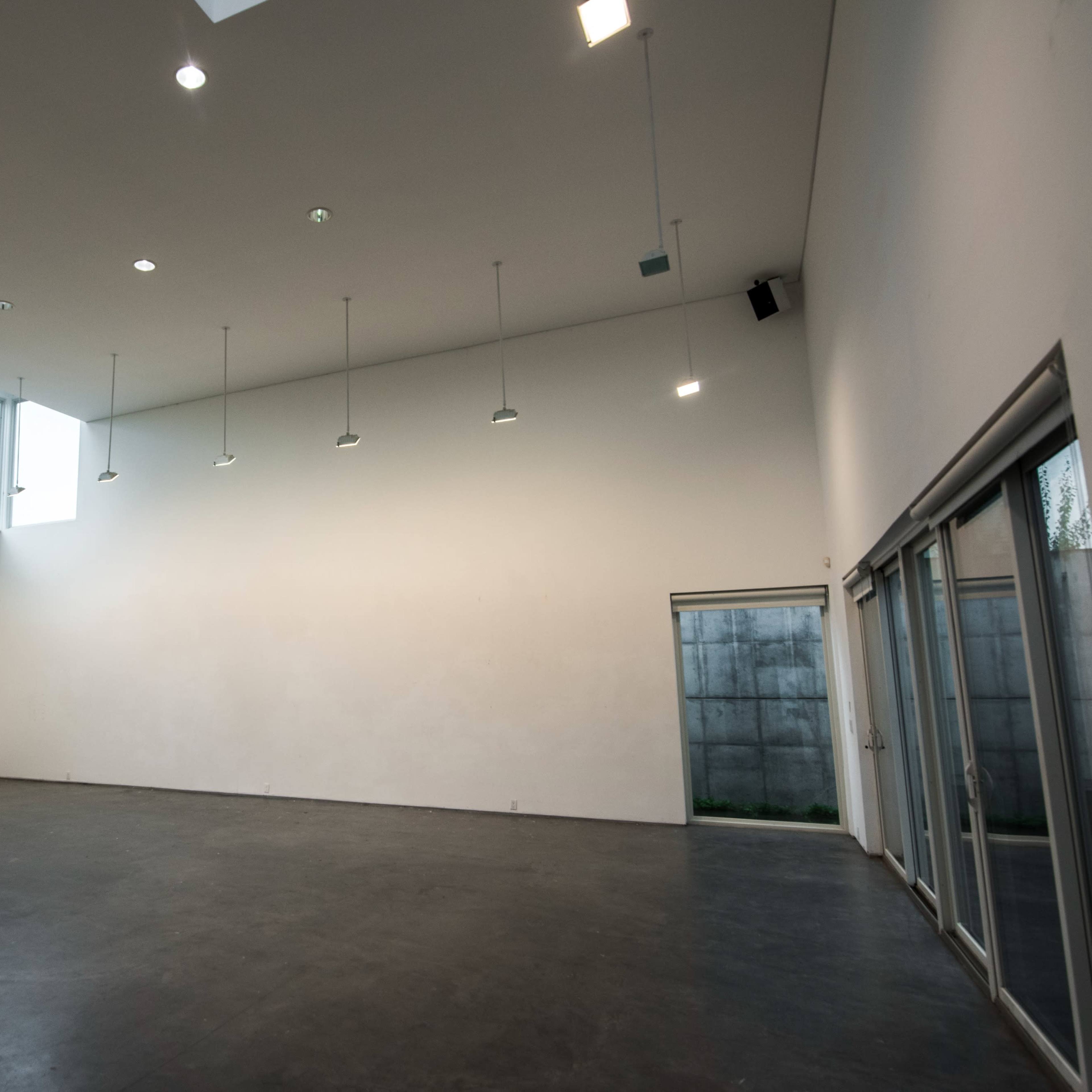 A spacious, empty room with high ceilings and large windows allowing natural light to enter.