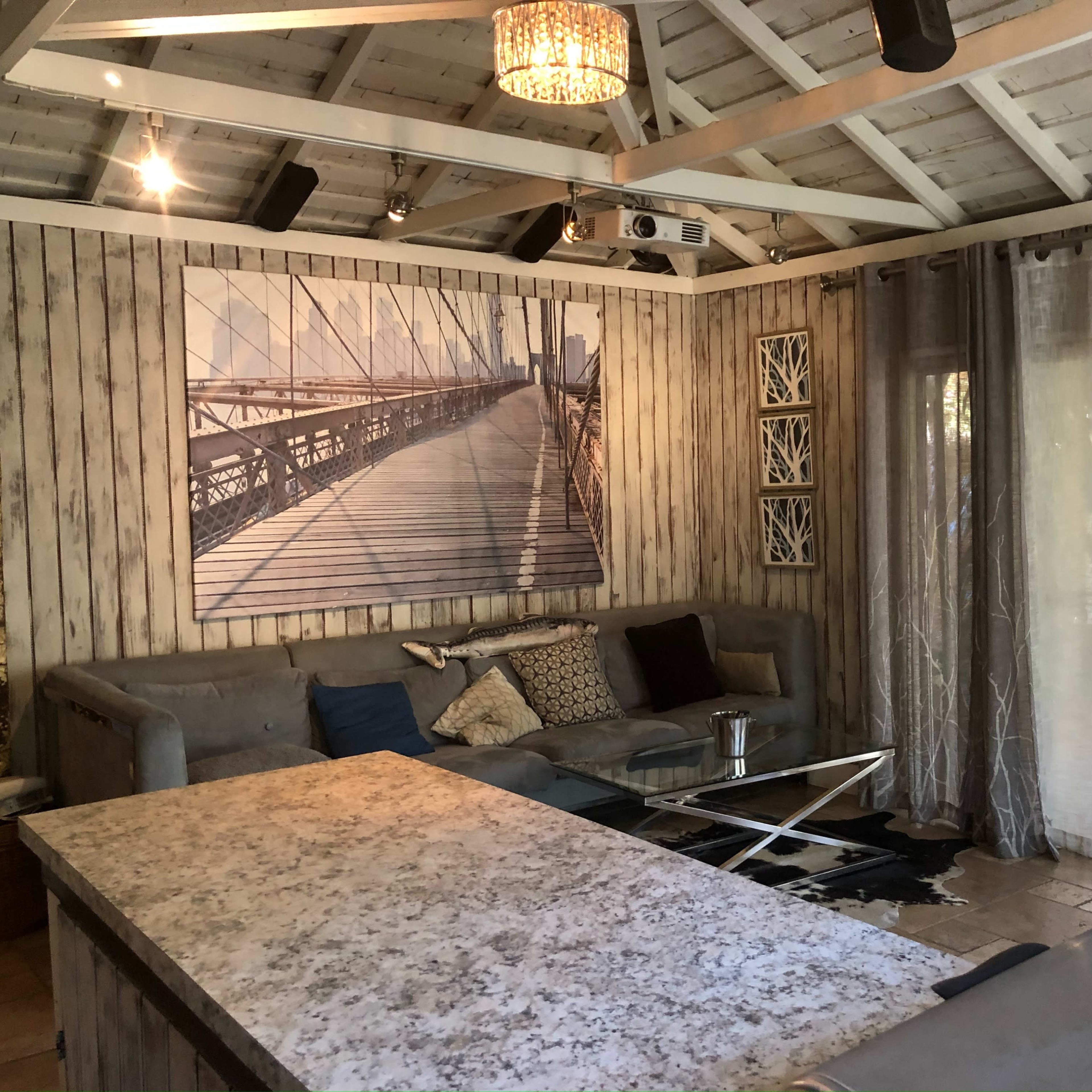 A rustic living room with a large bridge photograph on the wall and a quartz-topped table in the center.