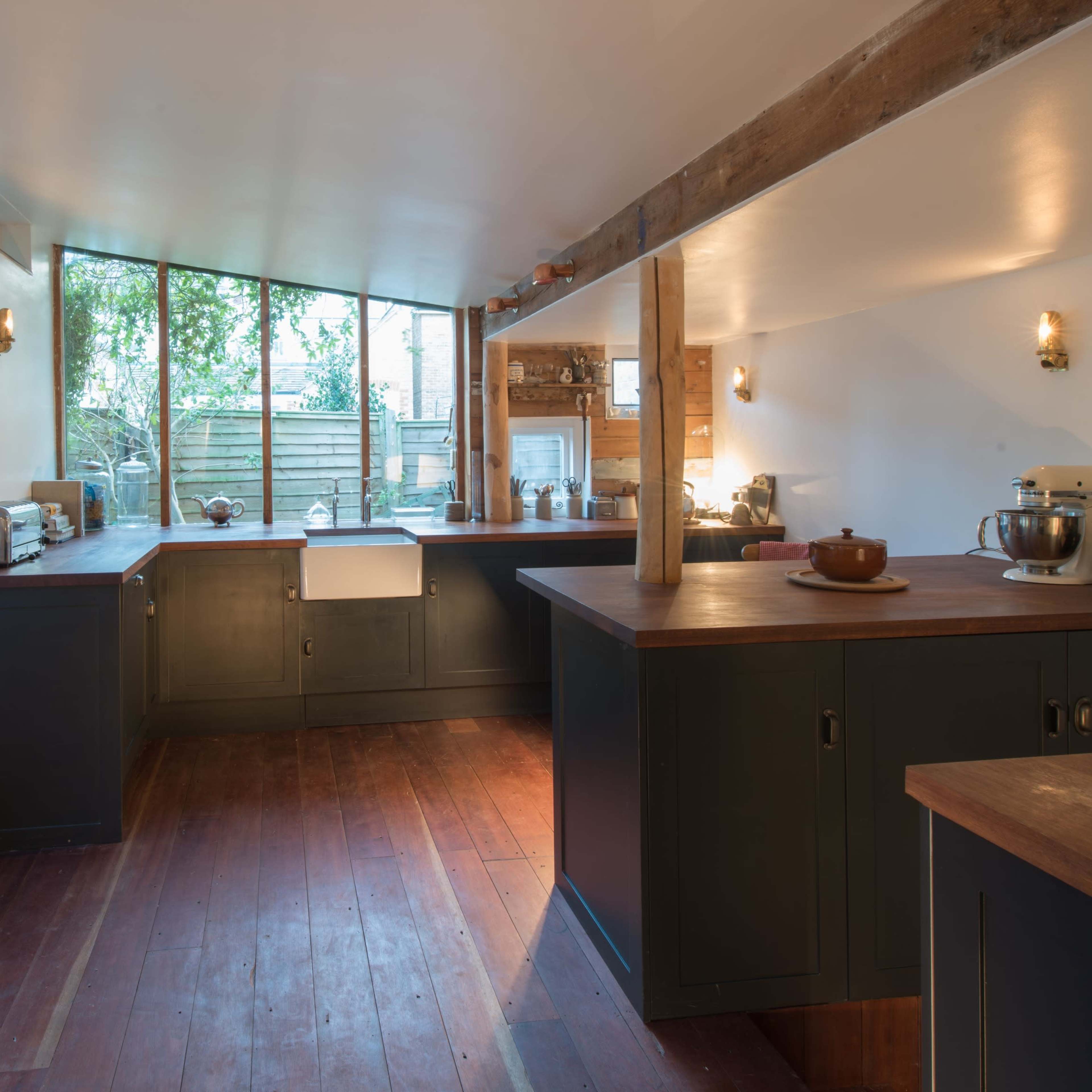 The kitchen features dark cabinets, a farmhouse sink, and large windows that illuminate the space with natural light.