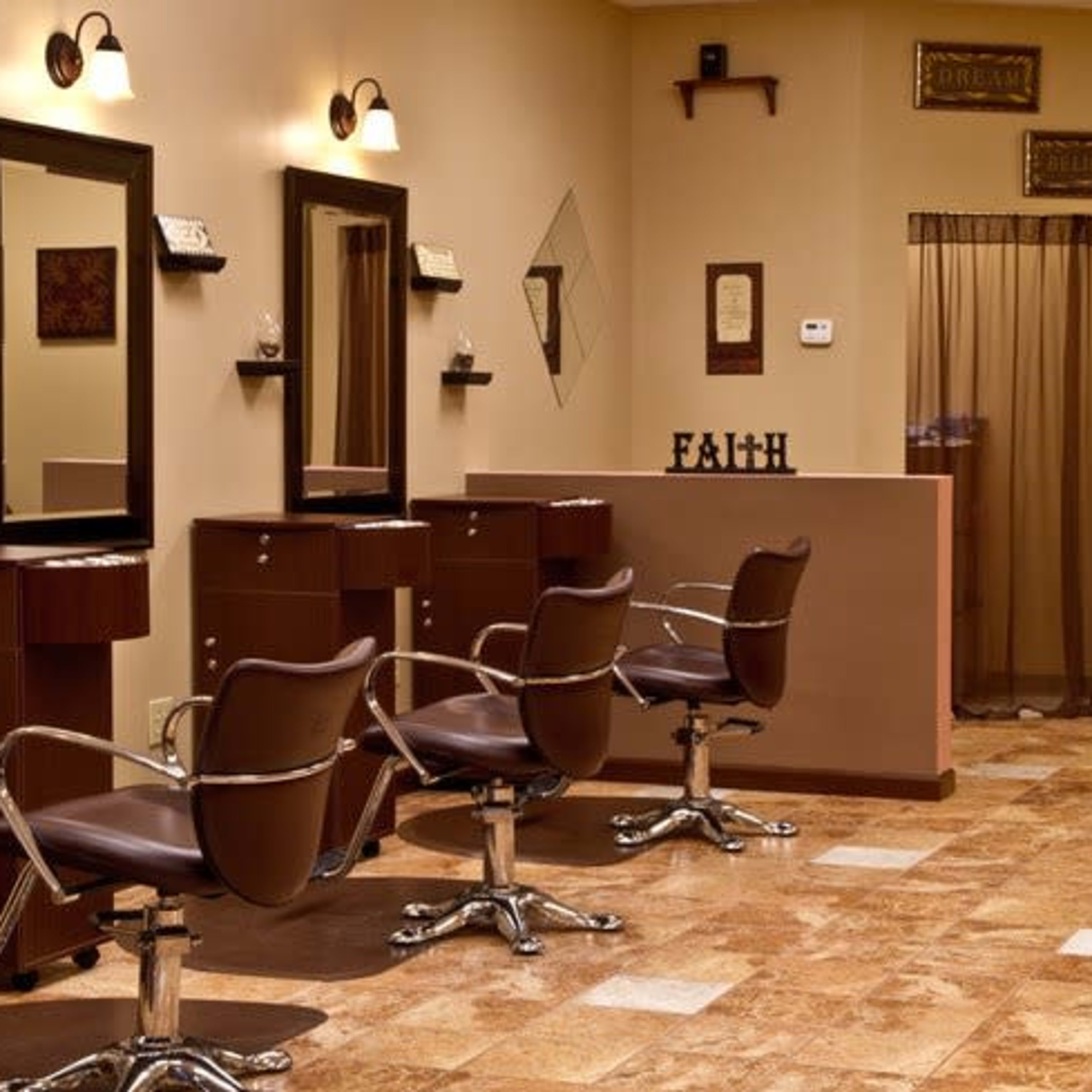 A hair salon interior with several styling stations, each featuring a mirror and a chair, and warm-toned walls.