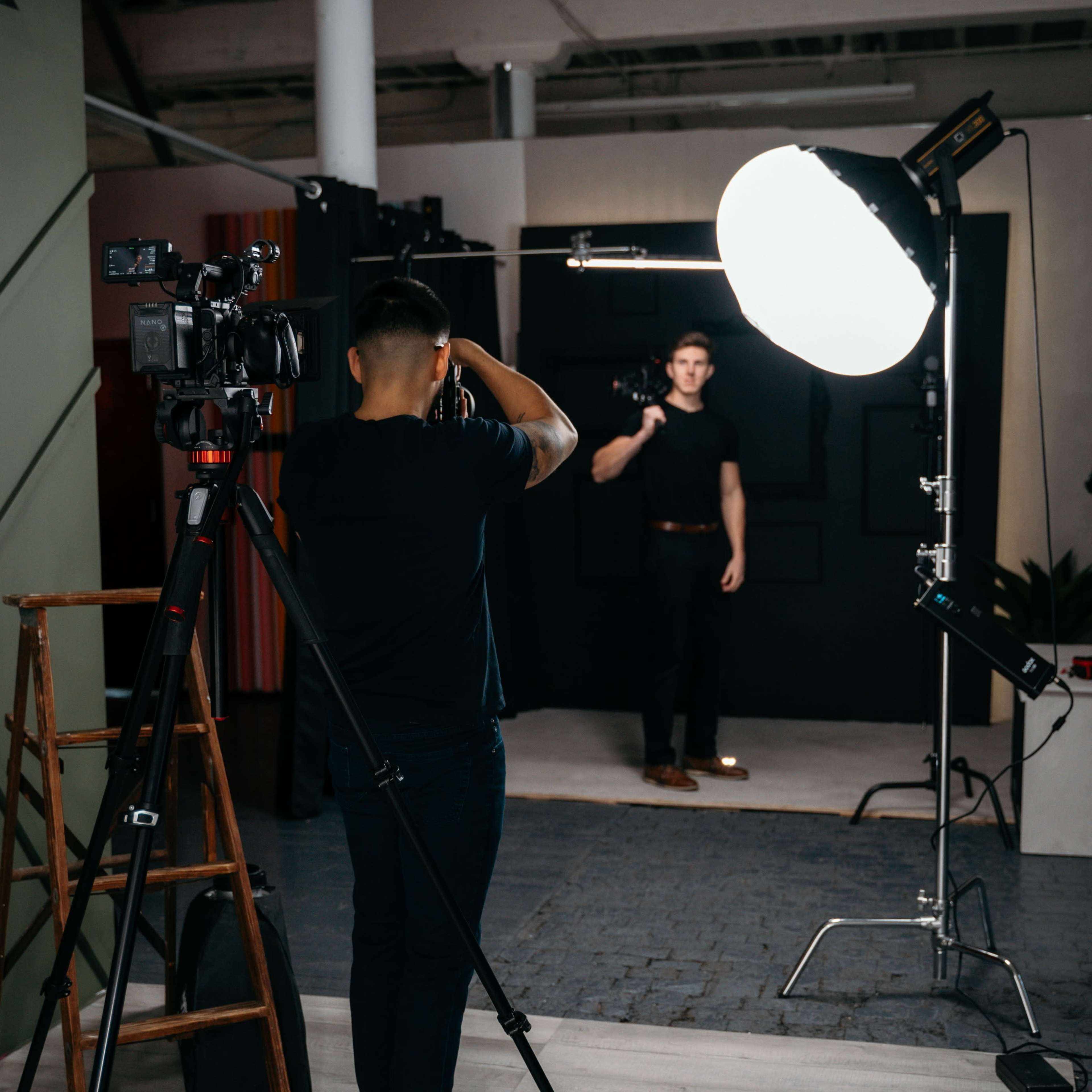 A photographer captures a model in a studio setting with multiple cameras and lighting equipment.