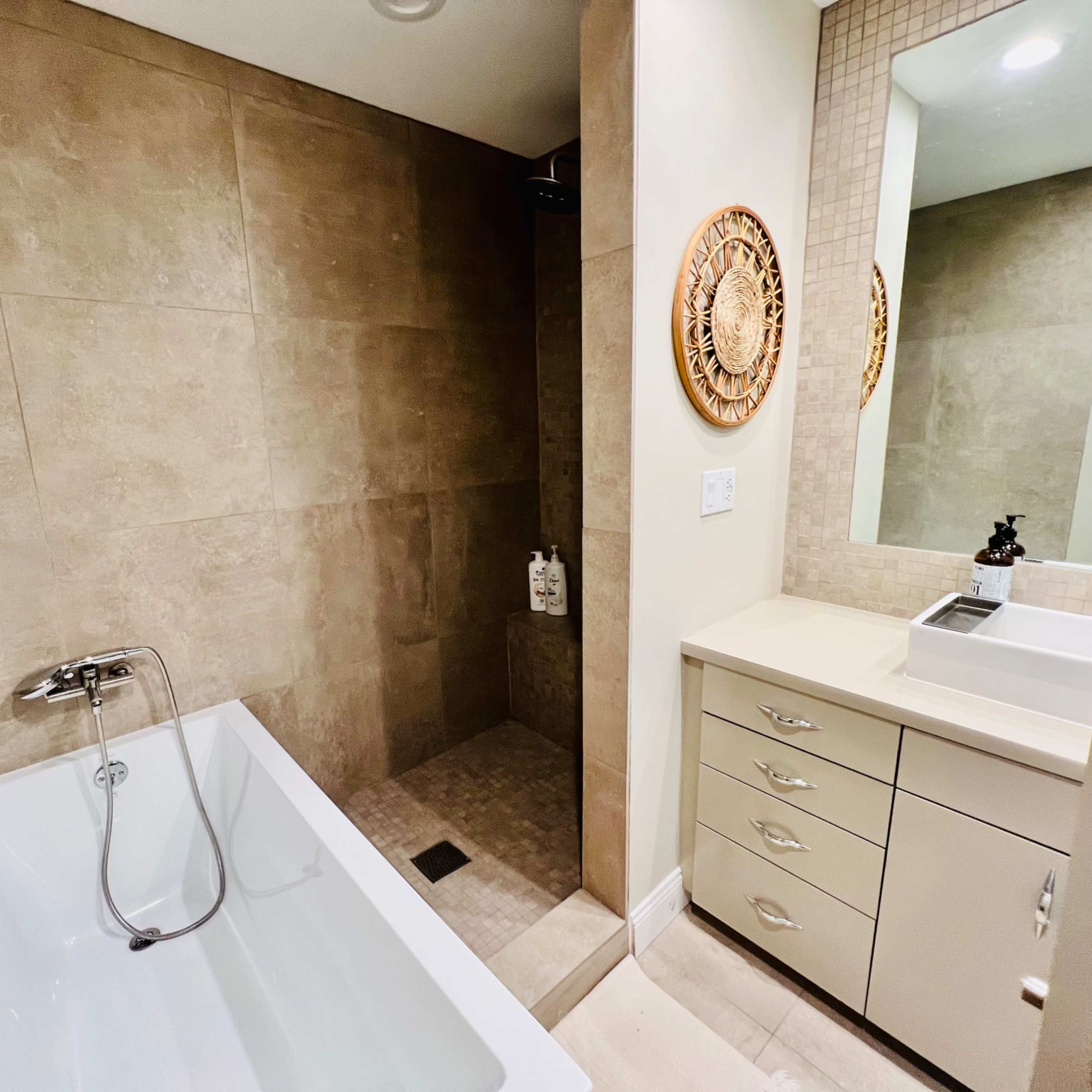 A modern bathroom featuring a bathtub, a separate shower area, and a vanity with drawers and a mirror.
