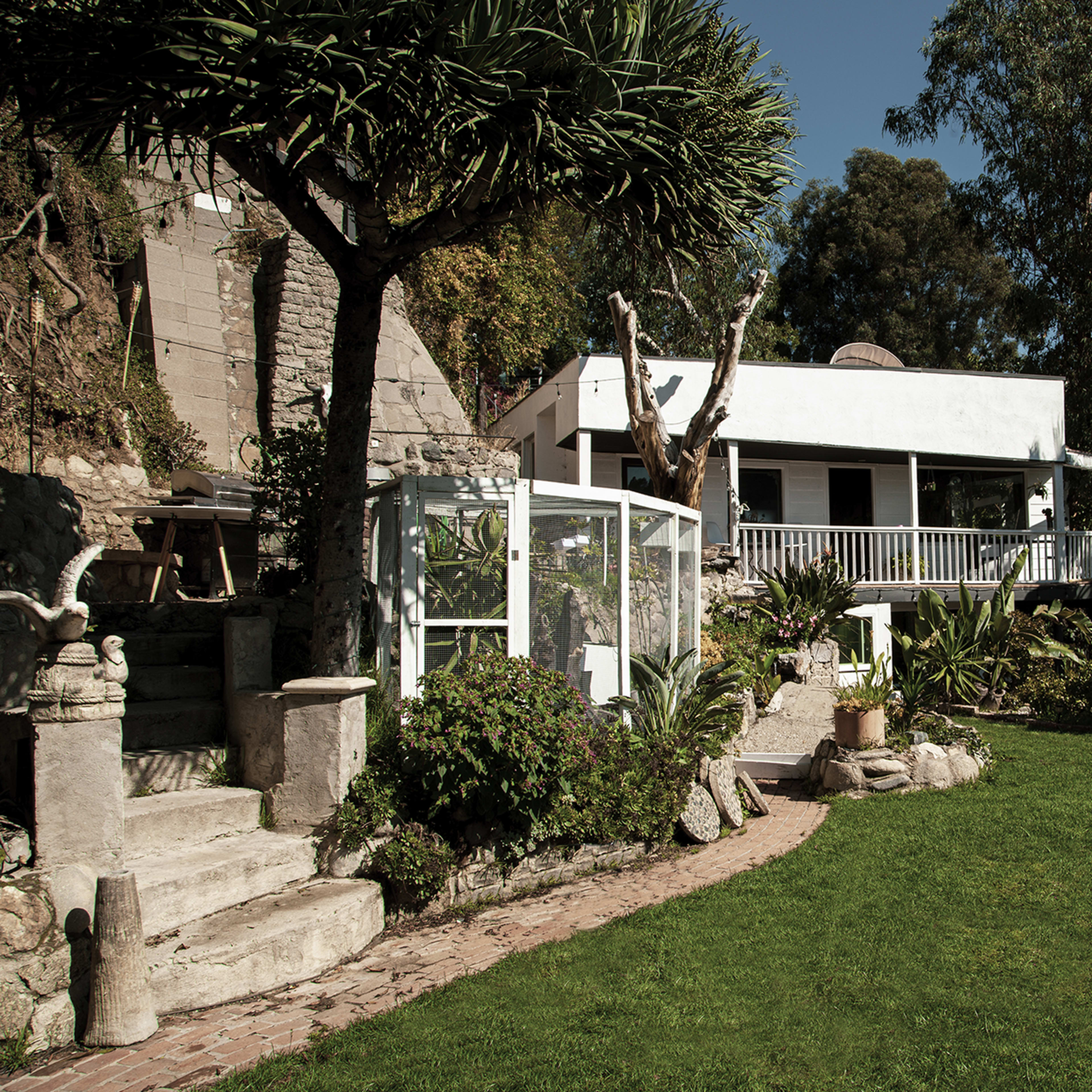 A garden with a well-maintained lawn, a modern house in the background, and decorative plants surrounding stone pathways.