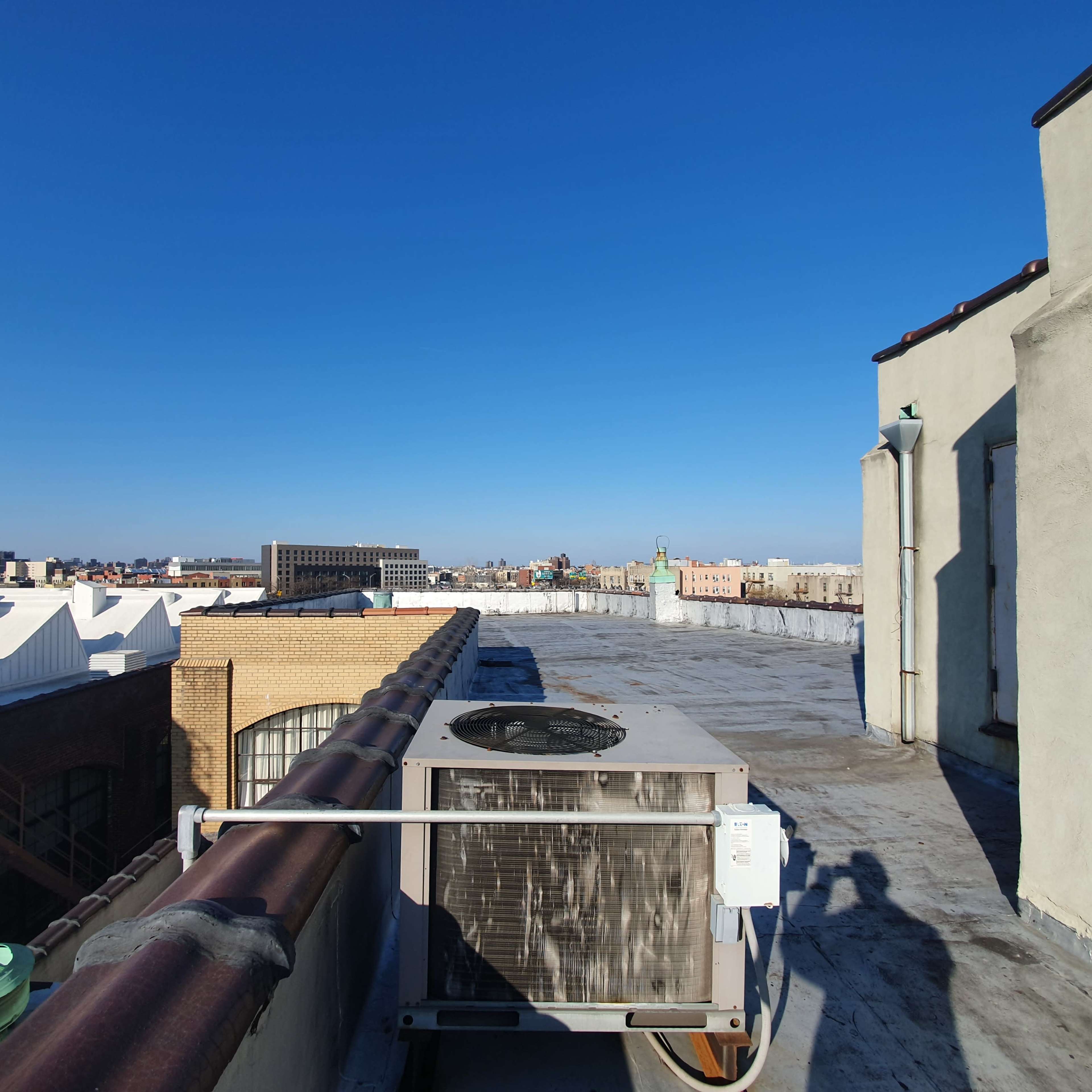 A rooftop scene with an air conditioning unit and a clear blue sky in the background.