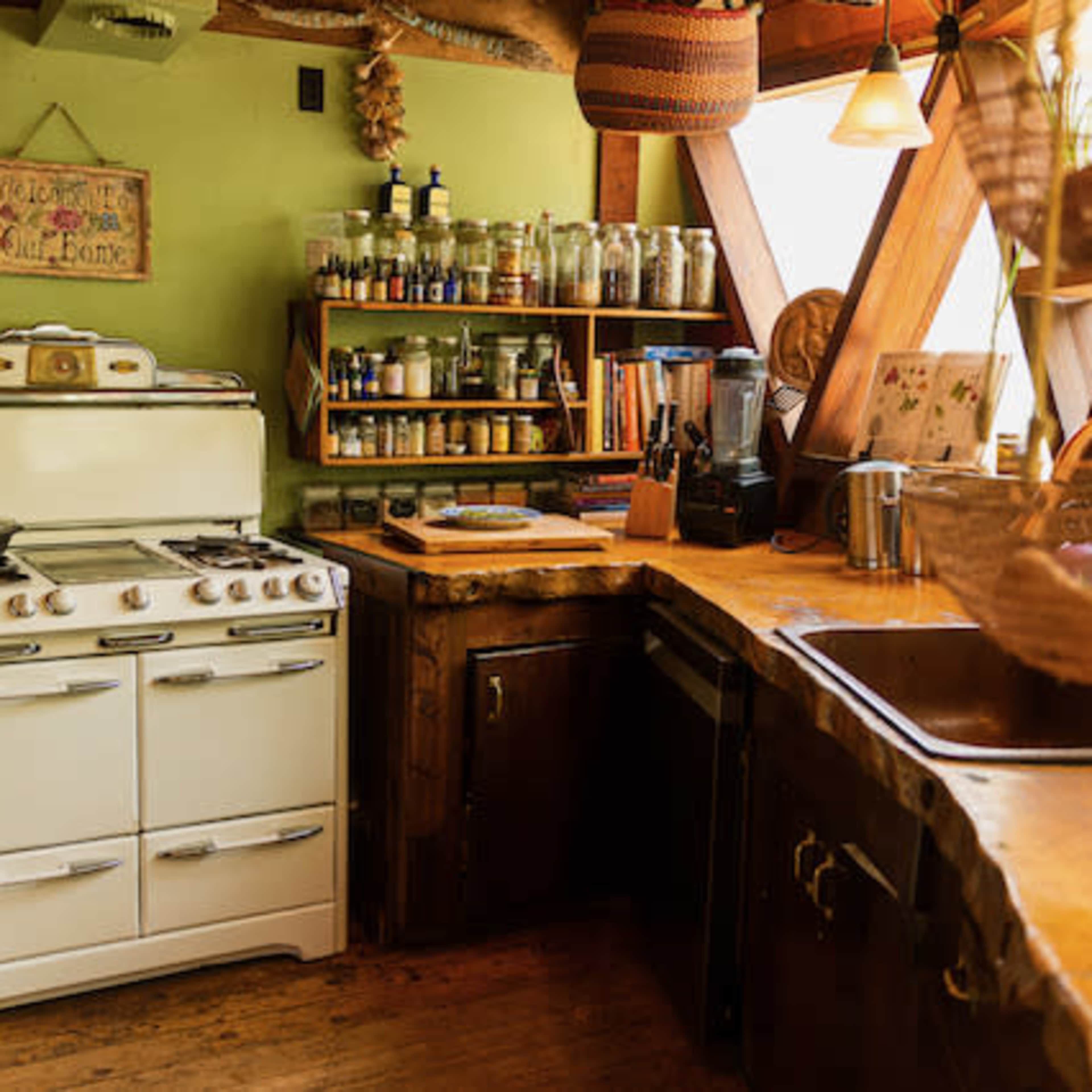 A cozy kitchen with a vintage white stove, wooden shelves filled with glass jars, and a natural wood countertop.